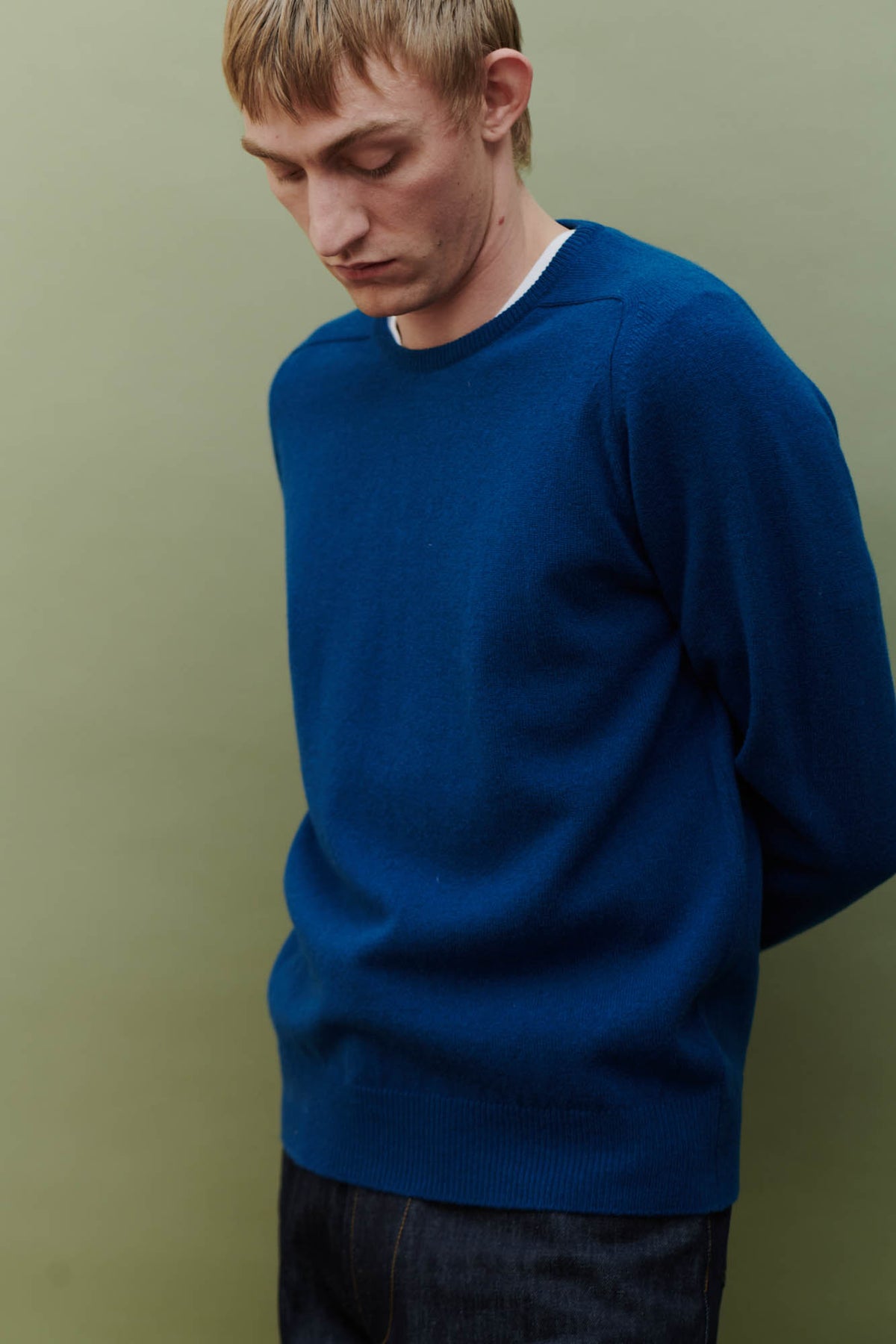 
            Image of side angle of white male looking down wearing men&#39;s lambswool saddle shoulder crew neck