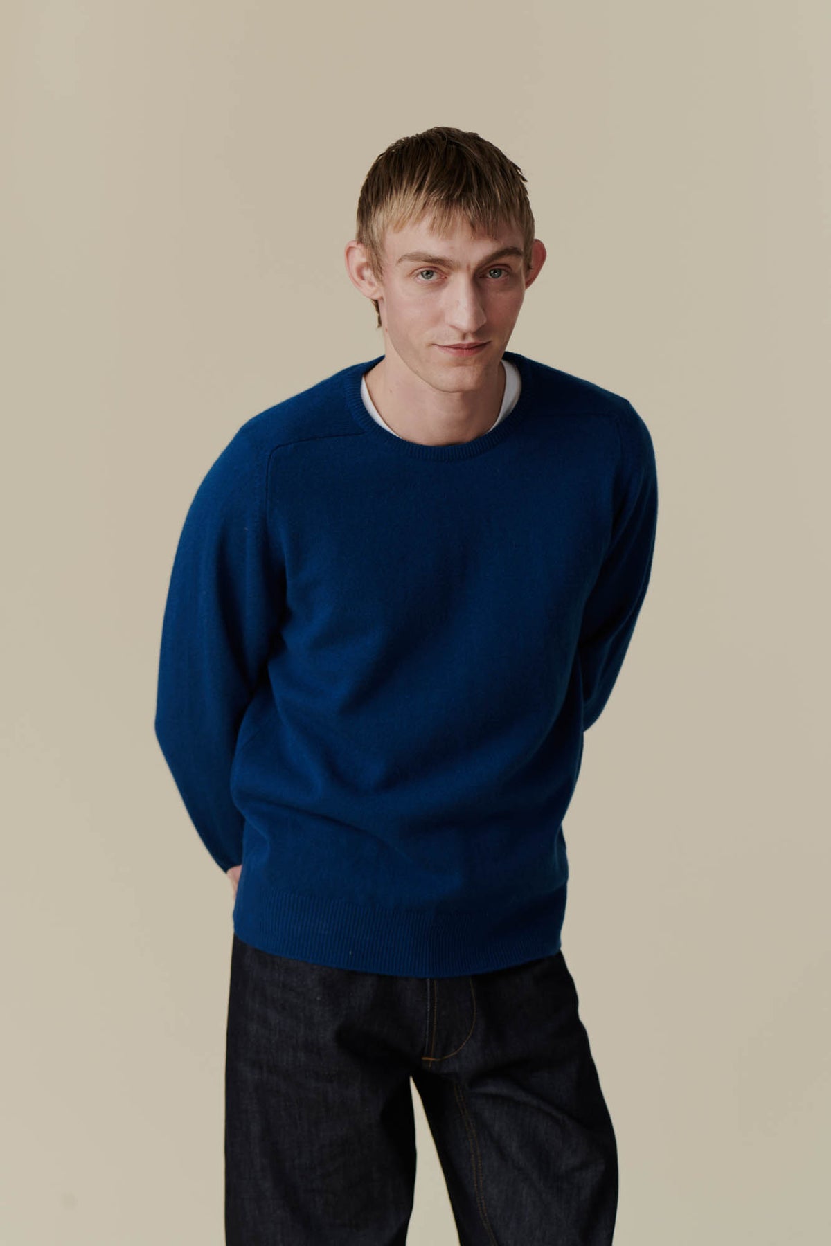 
            white male wearing lambswool saddle shoulder crew neck with arms behind back. 