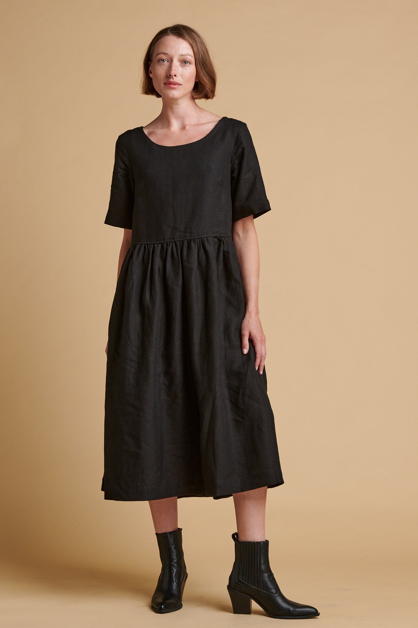 Female wearing crew neck gathered dress in black linen.