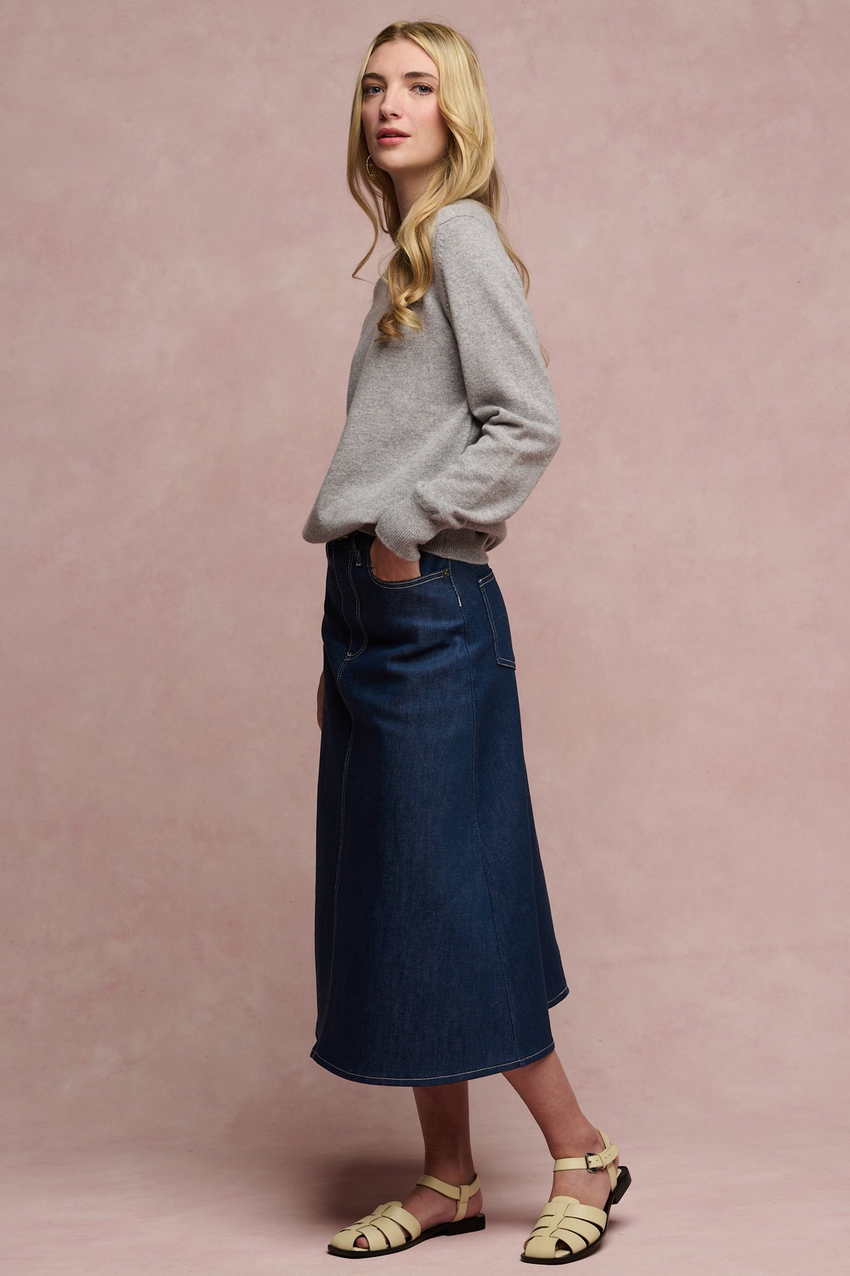 
            Side of female wearing Bobbie a line midi skirt in blue paired with lambswool crew neck jumper and sandals