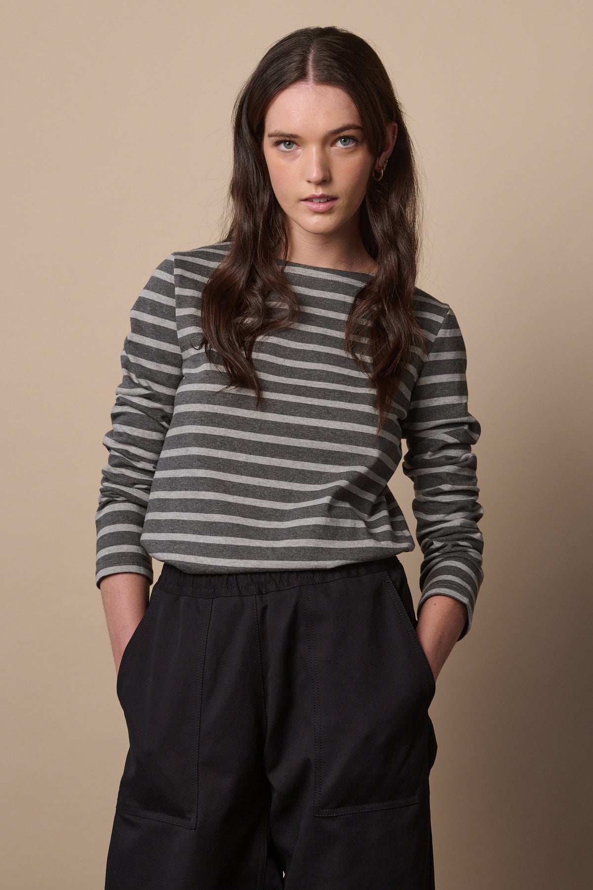 
            White female with long brunette hair wearing Breton in charcoal marl and grey marl tucked into trousers with sleeves pushed up the arm