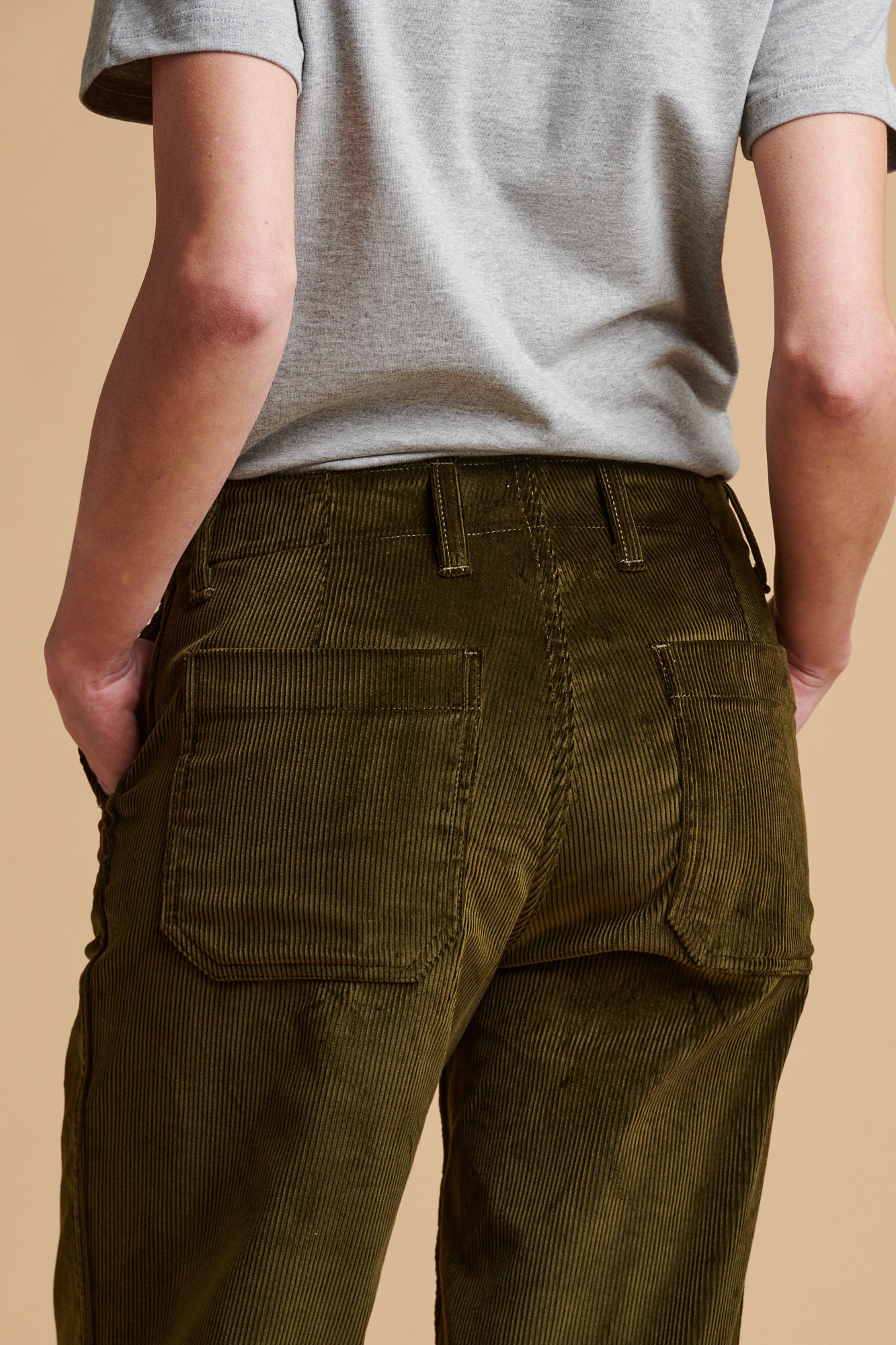 Close up of the back pockets and waistband of corduroy work trousers in olive.