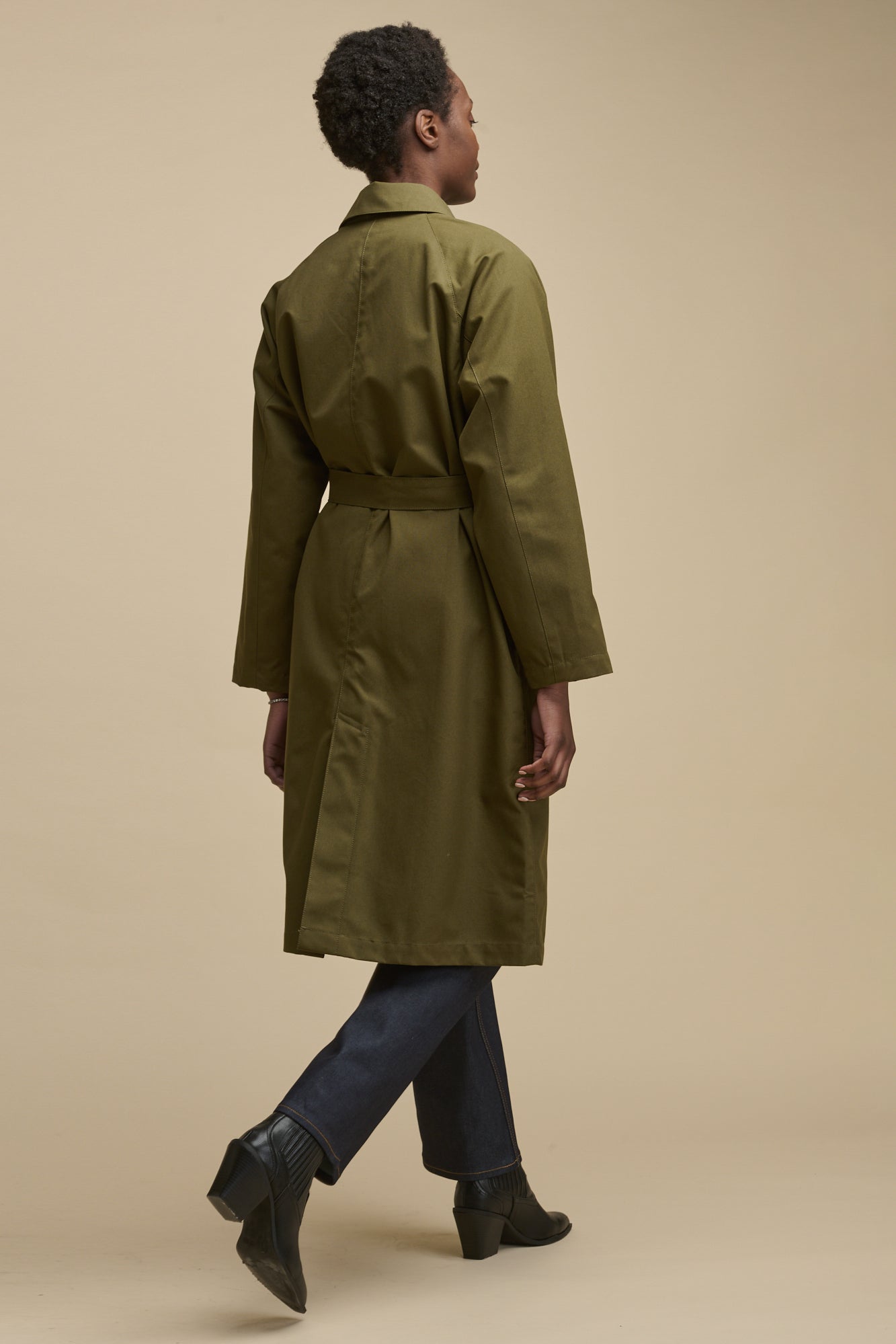 Full body image of the back of female wearing Frances Raglan Belted Raincoat in olive
