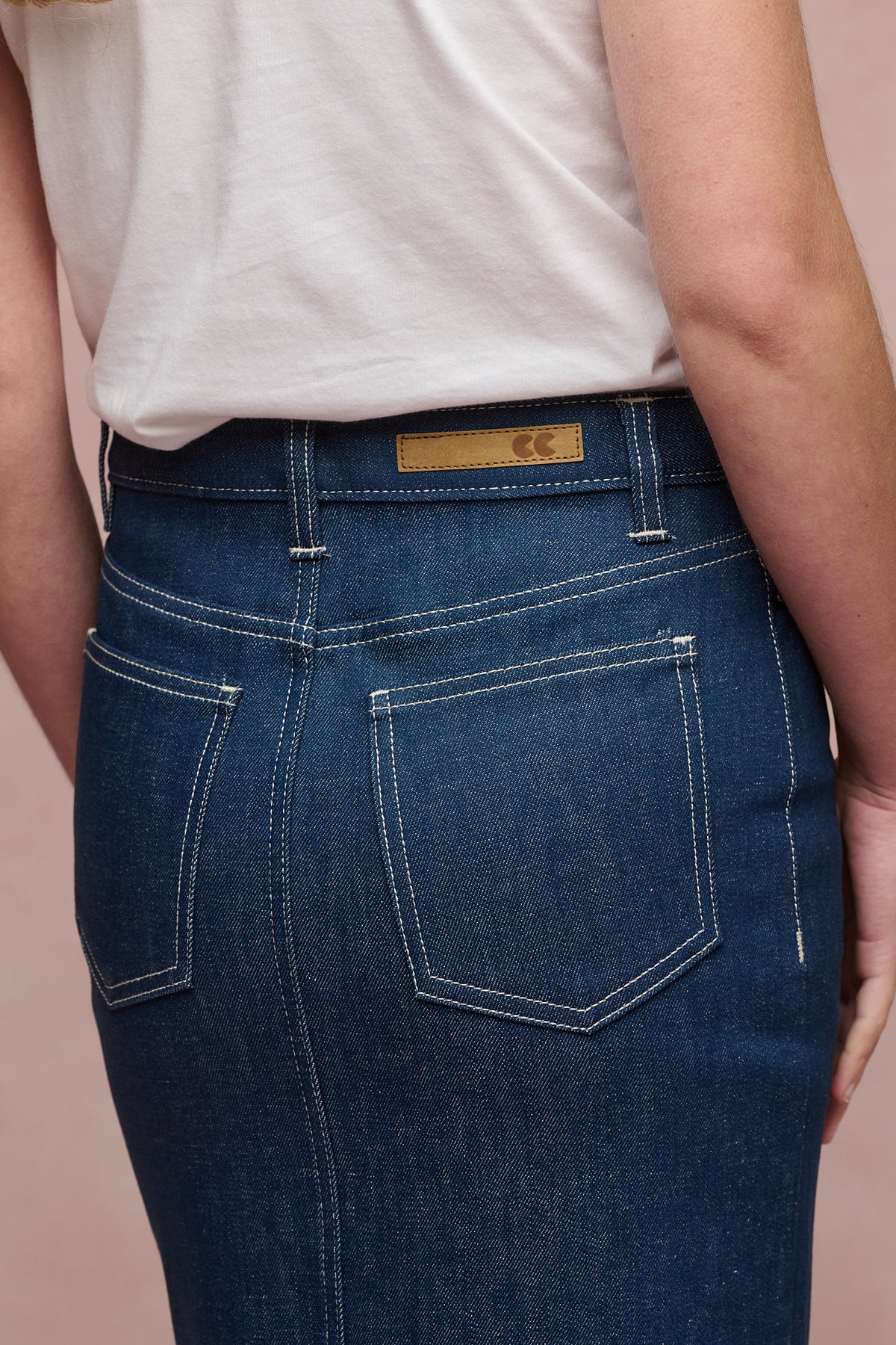 
            Close up of the back of Frankie denim maxi skirt in blue with jean CC logo patch and belt loops with two back pockets 