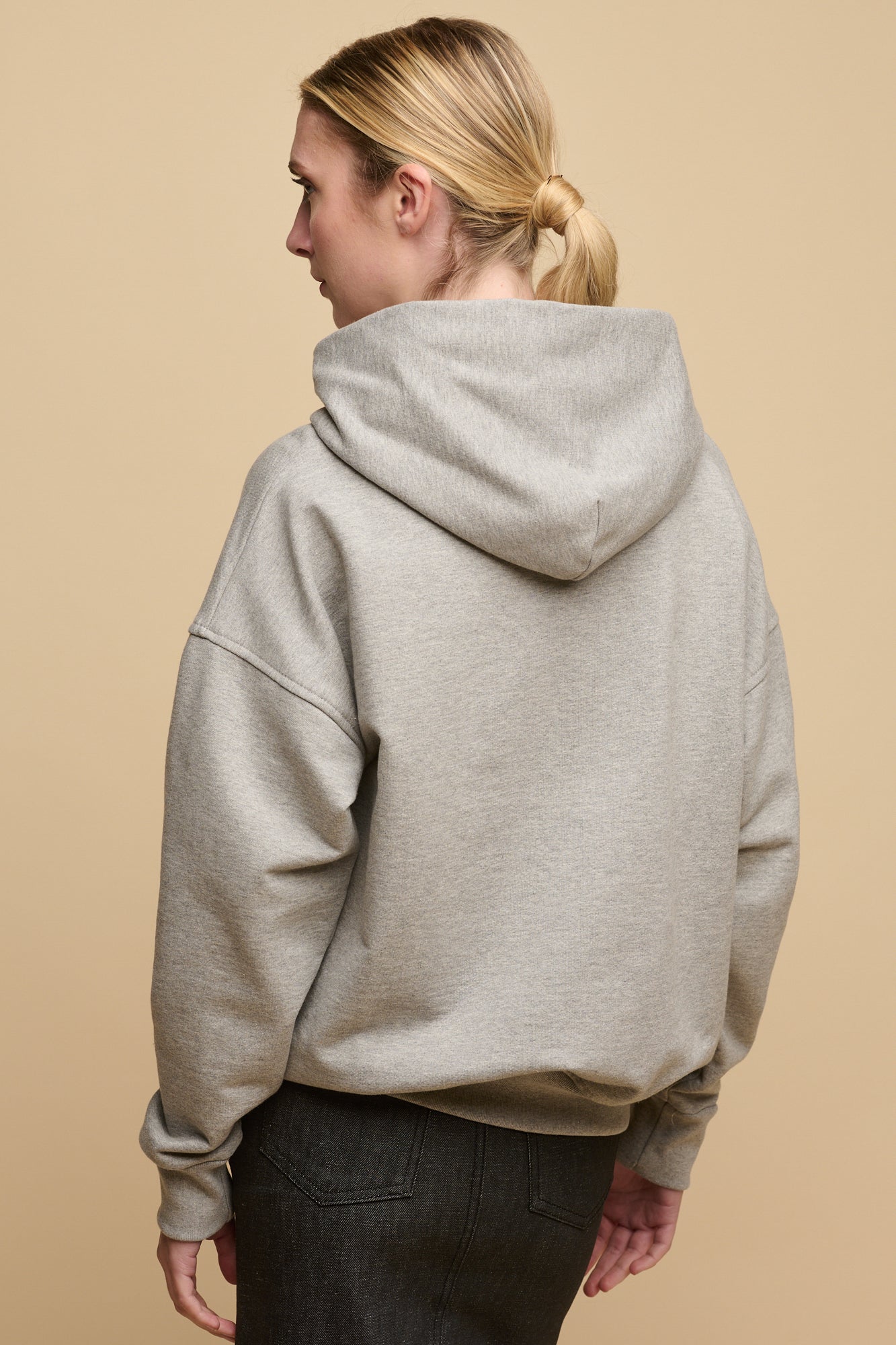 Back of female wearing heritage hooded sweatshirt in grey paired with denim maxi skirt in black