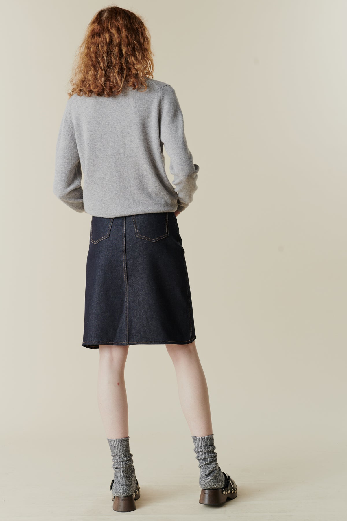 
            Female wearing knee length jean skirt in indigo with back pockets