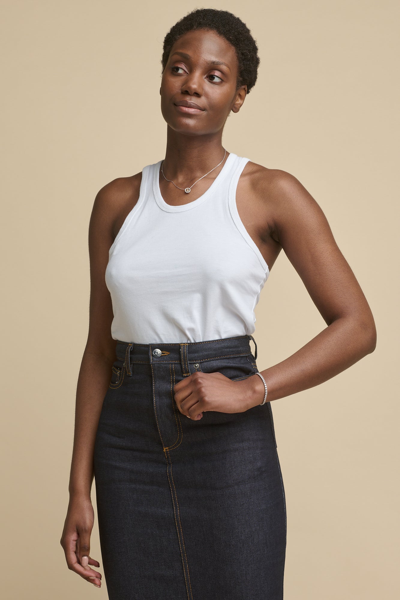 Thigh up image of the front of black female wearing racer back vest in white