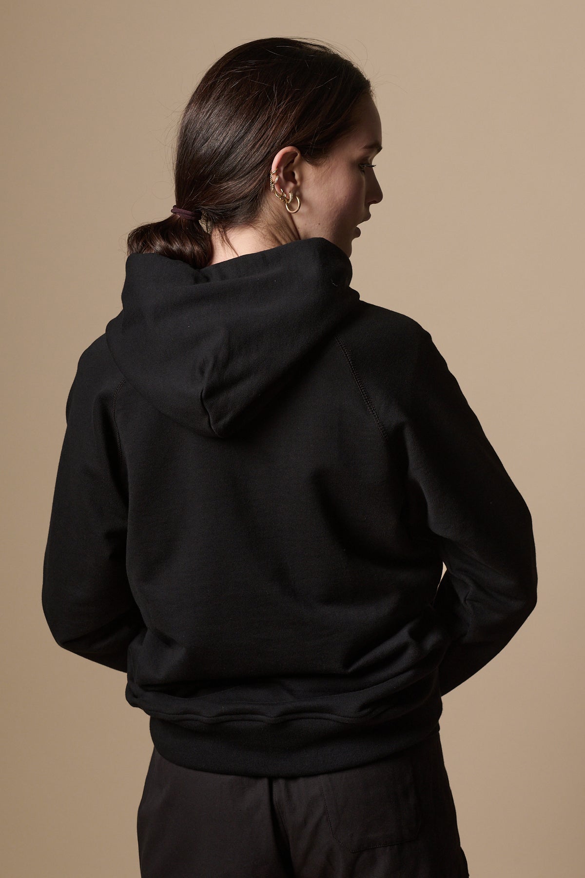
            Back of female wearing women&#39;s raglan hooded sweatshirt plastic free in black