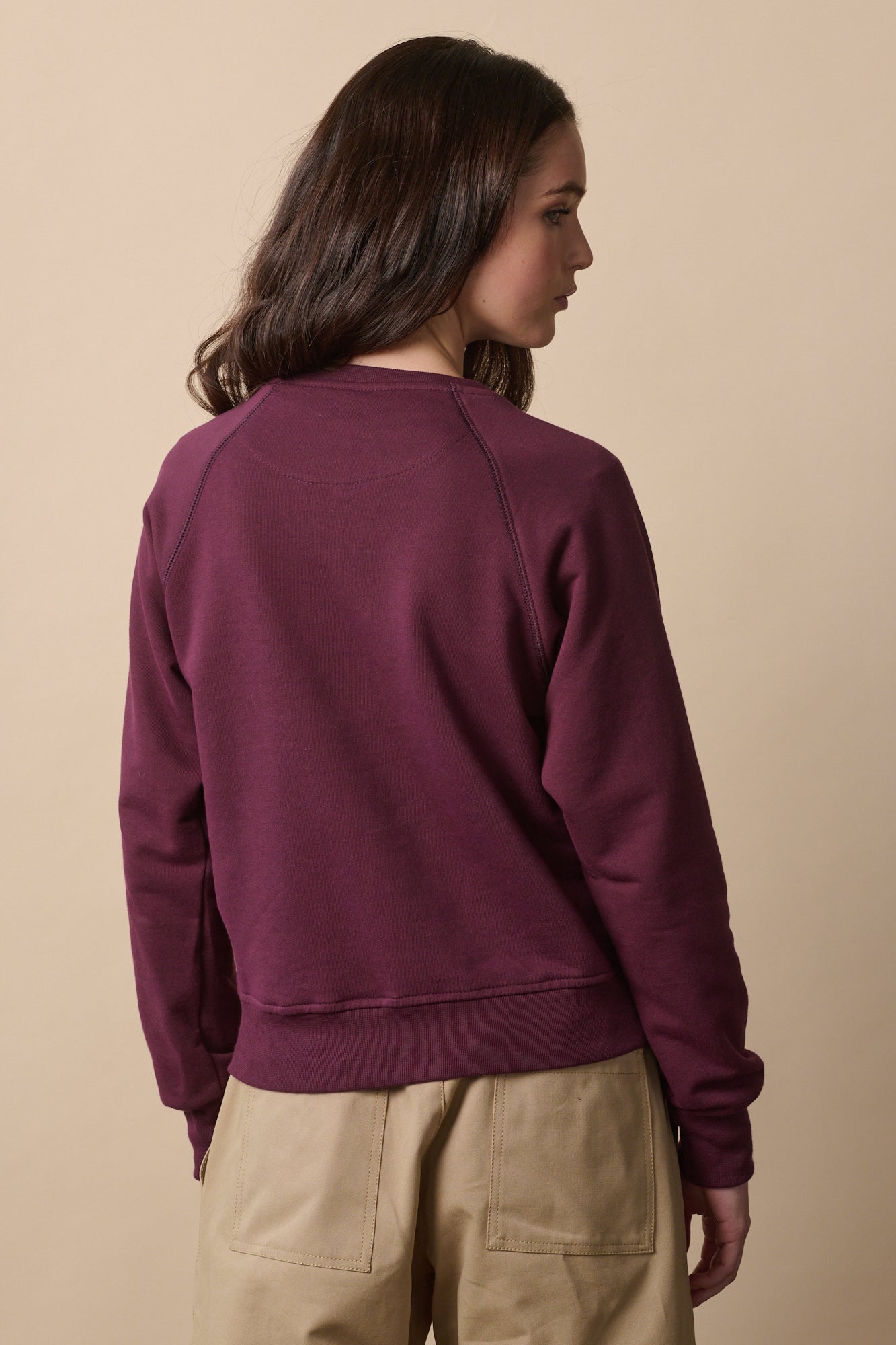 thigh up of the back of female wearing raglan sweatshirt in plum