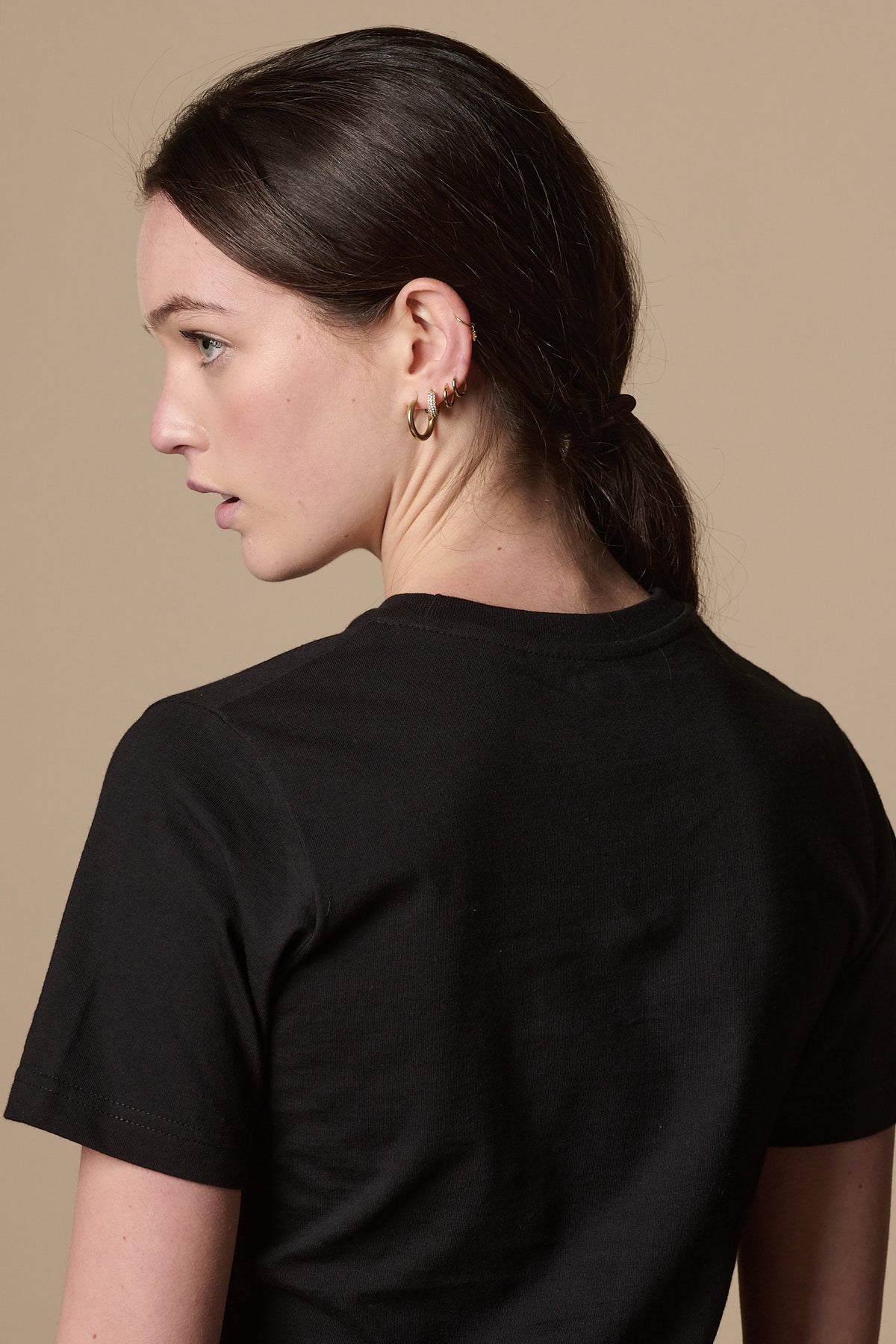 
            Image showing back of white female wearing short sleeve, crew neck t shirt plastic free in black.