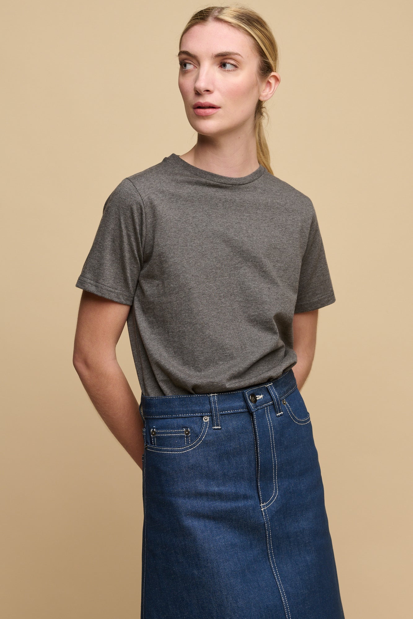 Thigh up image of female wearing short sleeve t shirt in charcoal paired with Bobbie denim midi skirt in blue