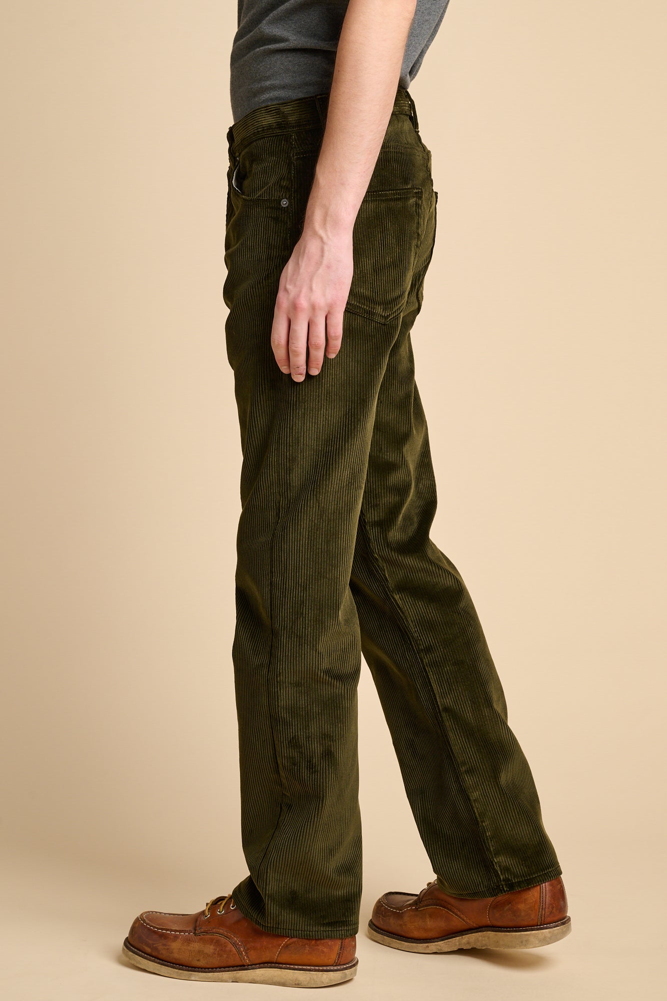 The side of male wearing dark olive corduroy jeans.