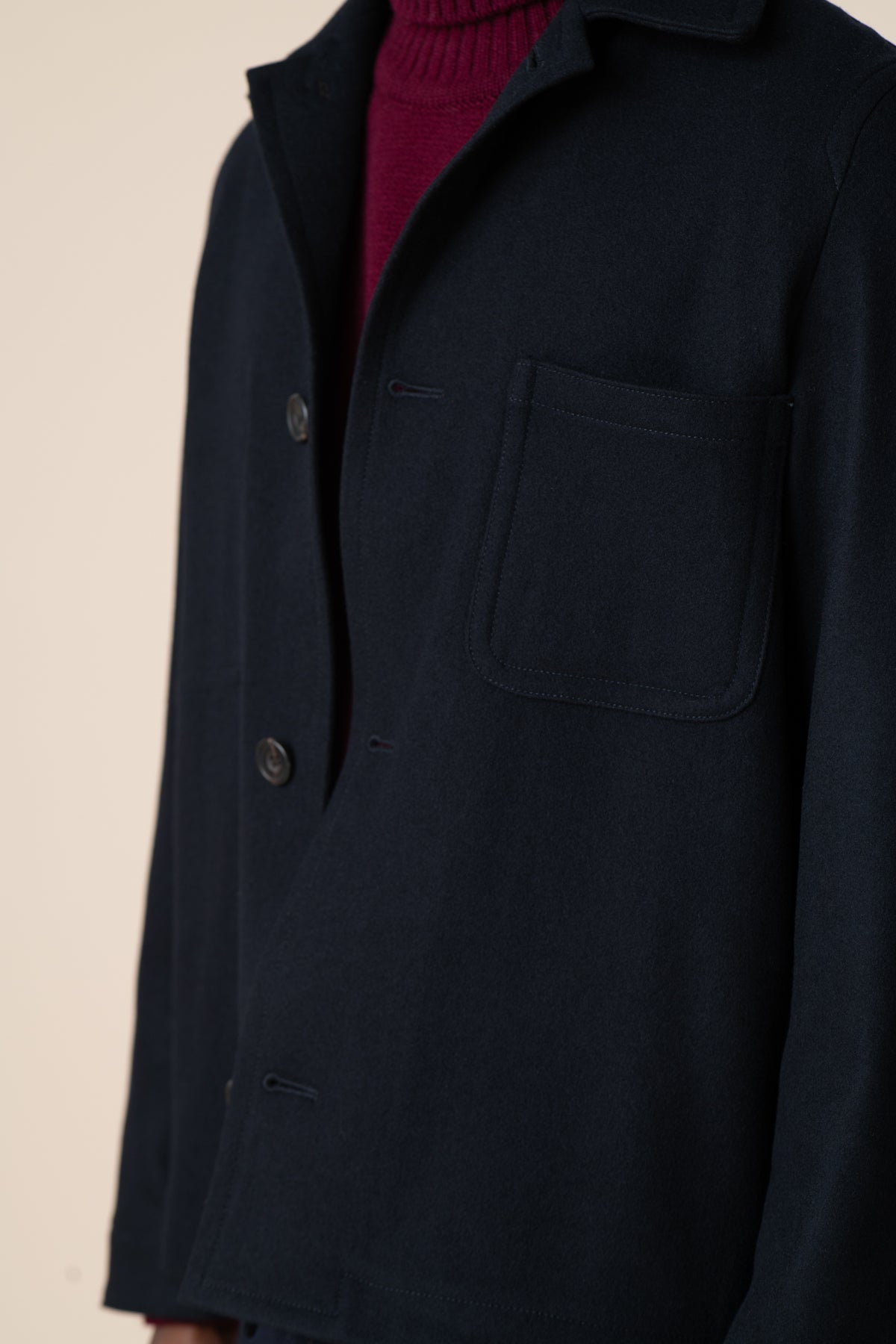 
            Detail image of top pocket of Arthur wool chore jacket in navy, layered over lambswool roll neck in burgundy.