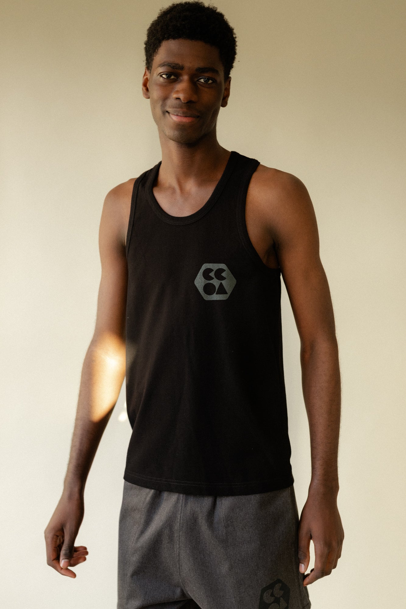 Smiley, male wearing breathable racer back vest plastic free in black with CCOA logo