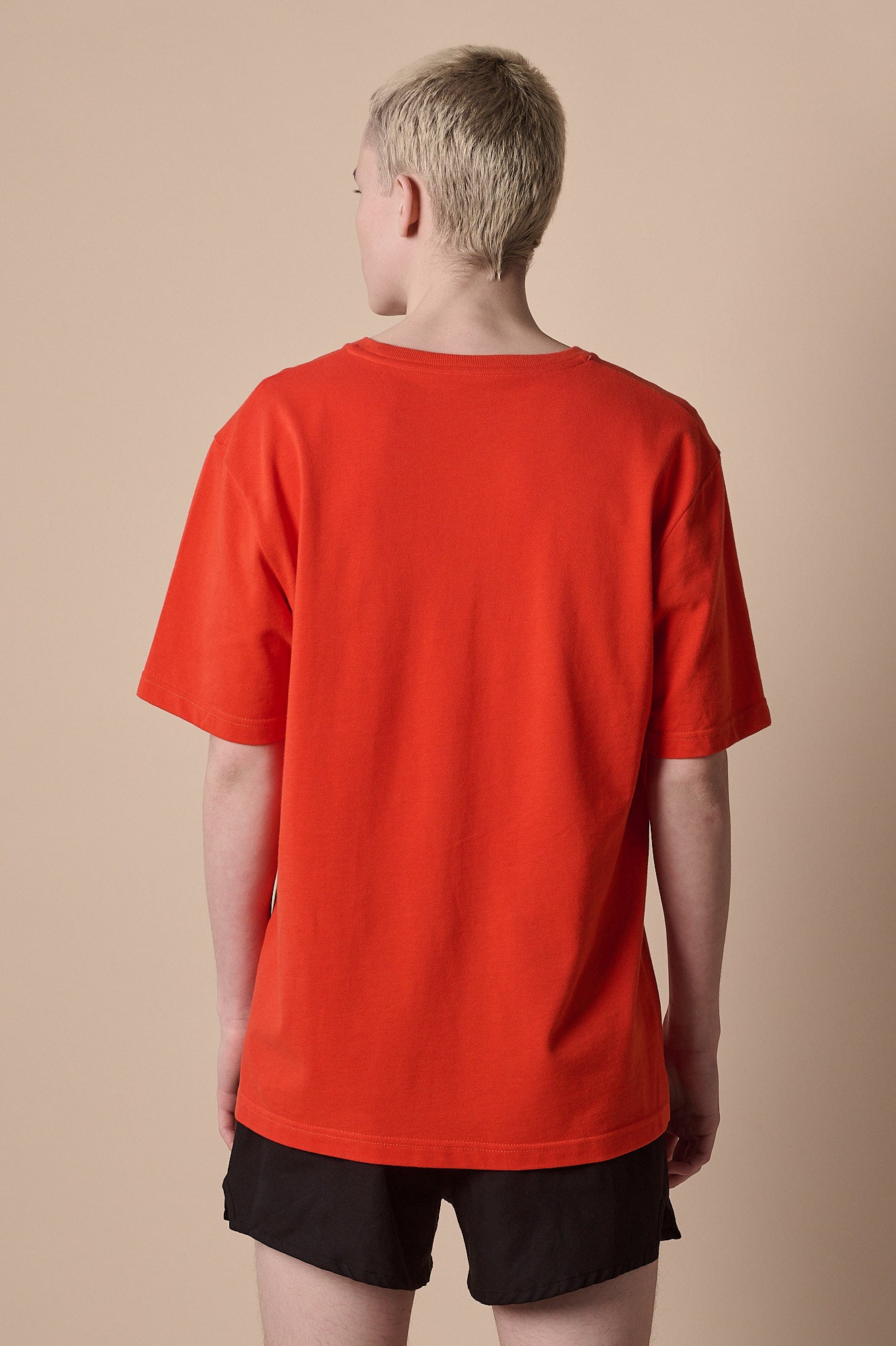 Image of the back of male wearing breathable t shirt plastic free in flame red with CCOA logo