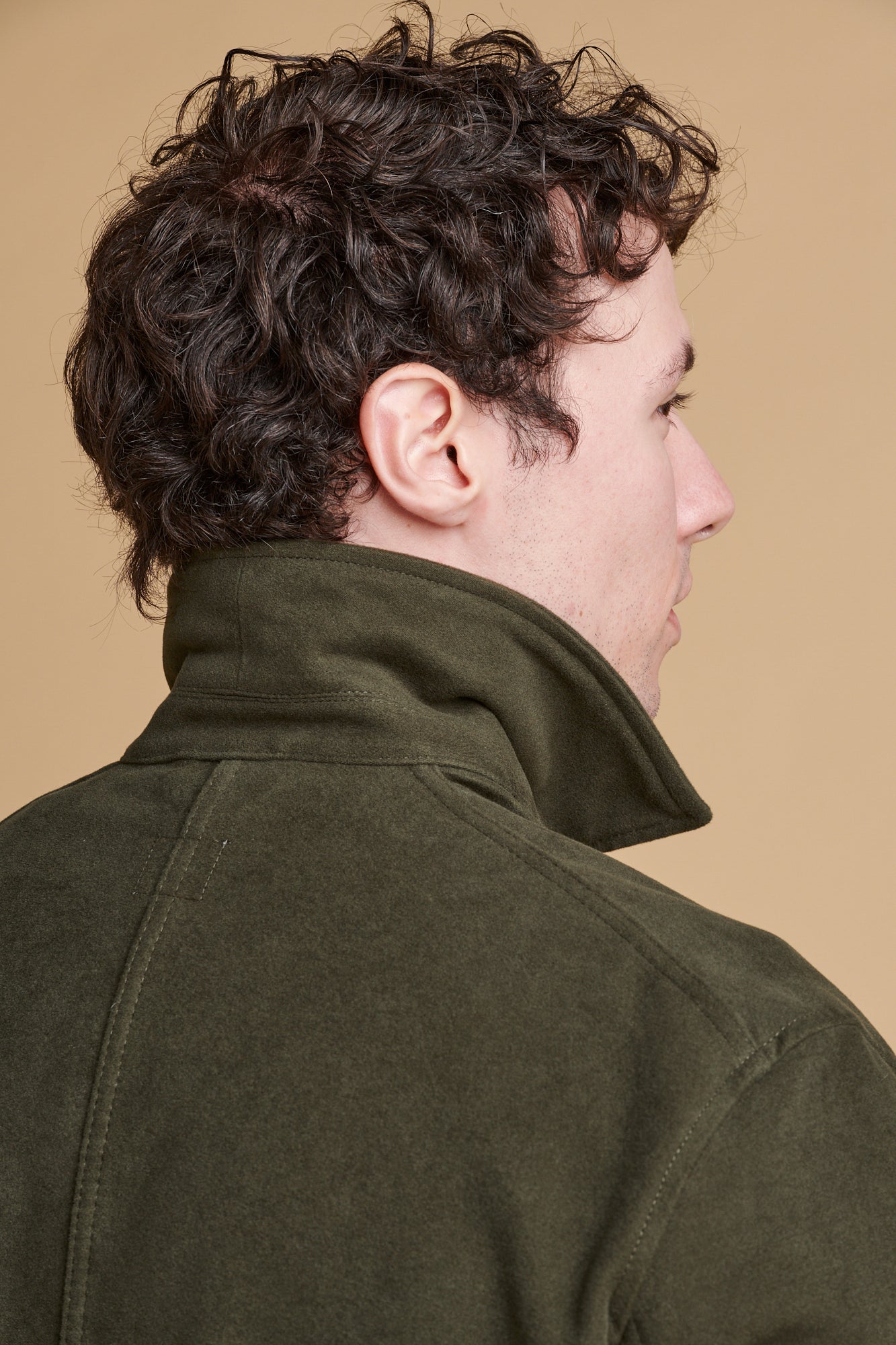 The back of male wearing Carter moleskin chore jacket in dark olive with collar up.