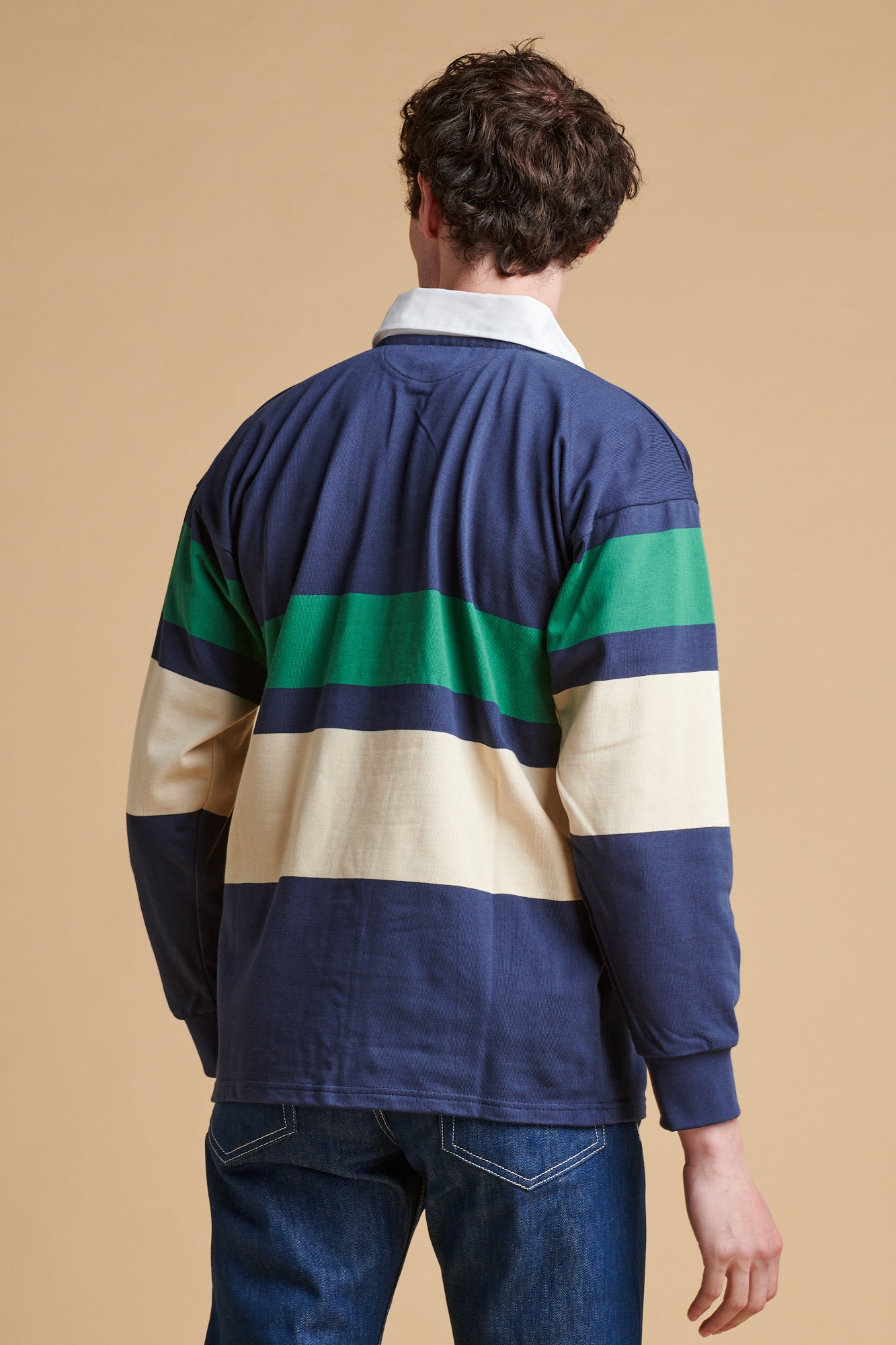 The back of male wearing chest striped rugby shirt in ecru navy bottle green.