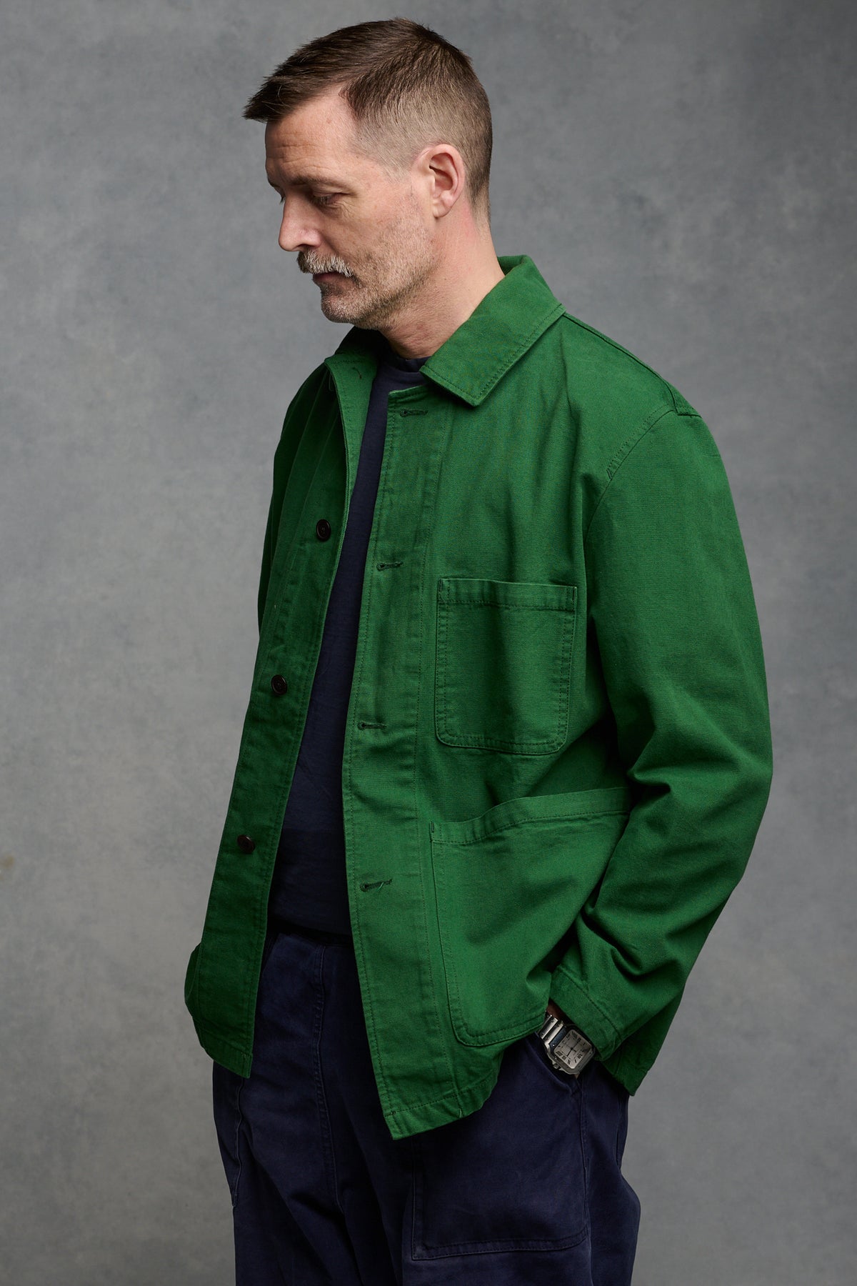 
            Thigh up image of Community Clothing founder Patrick Grant wearing men&#39;s chore jacket in bottle green, worn with cameraman pants in navy 