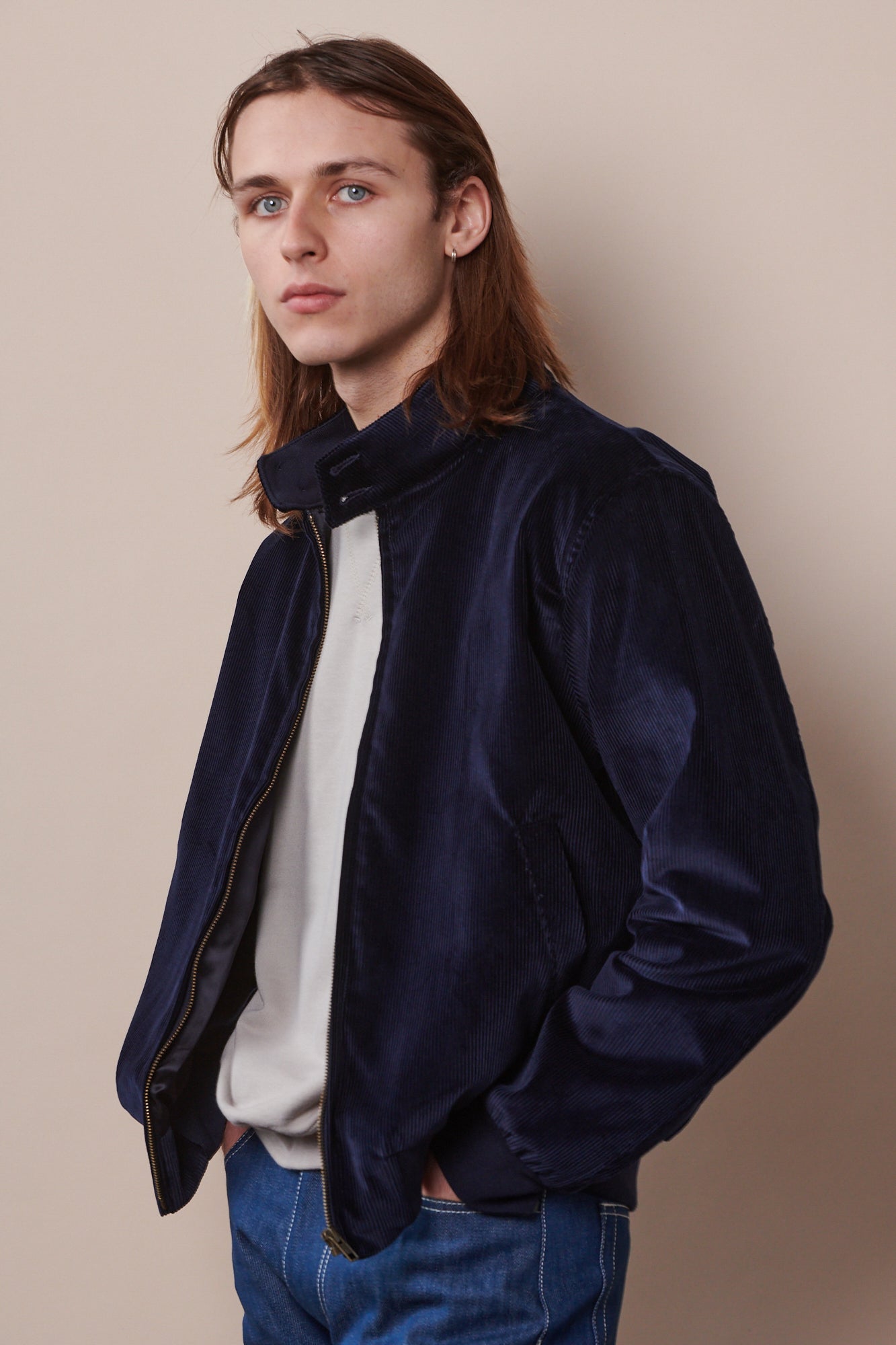 Thigh up image of male at an angle wearing corduroy Harrington in navy unzipped