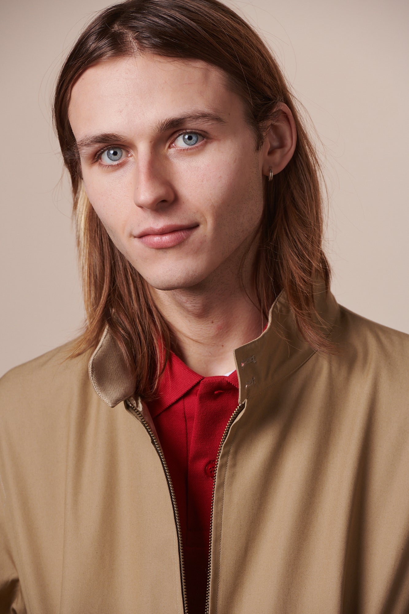 Portrait of white male with brown hair wearing Harrington jacket unzipped and crimson polo shirt underneath