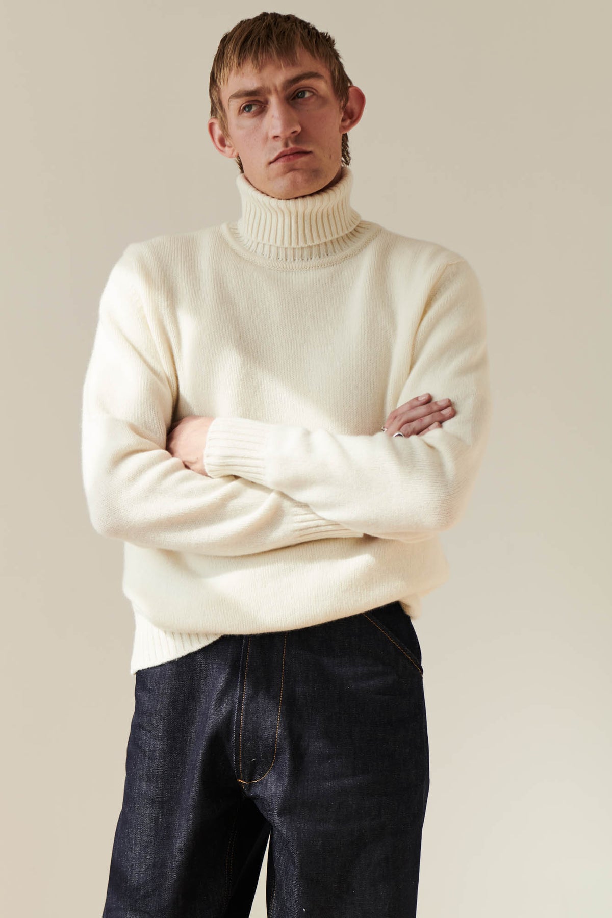 
            Thigh up shot of male wearing lambswool roll neck in ecru