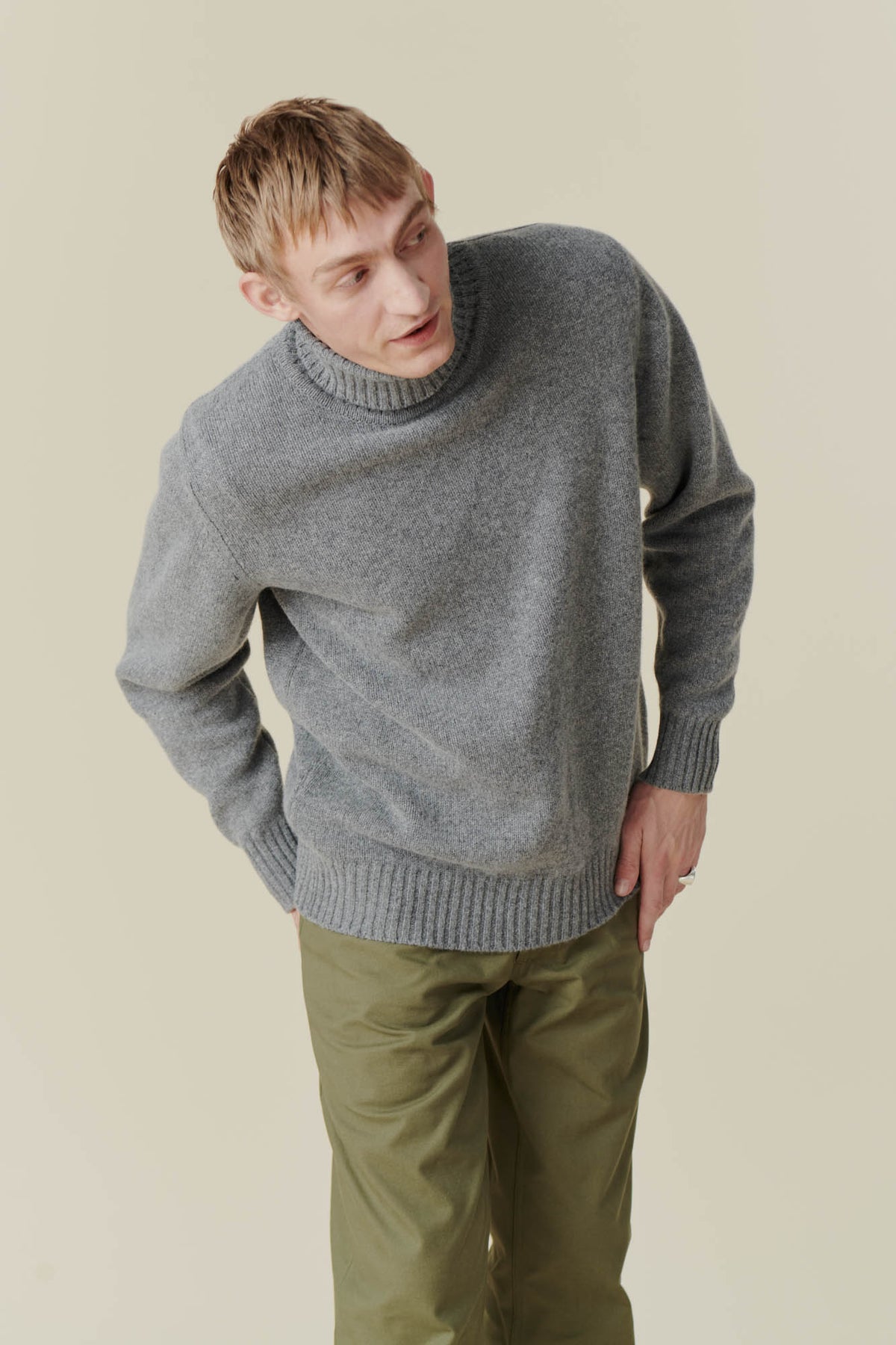 
            White male wearing grey roll neck jumper and olive cameraman pant