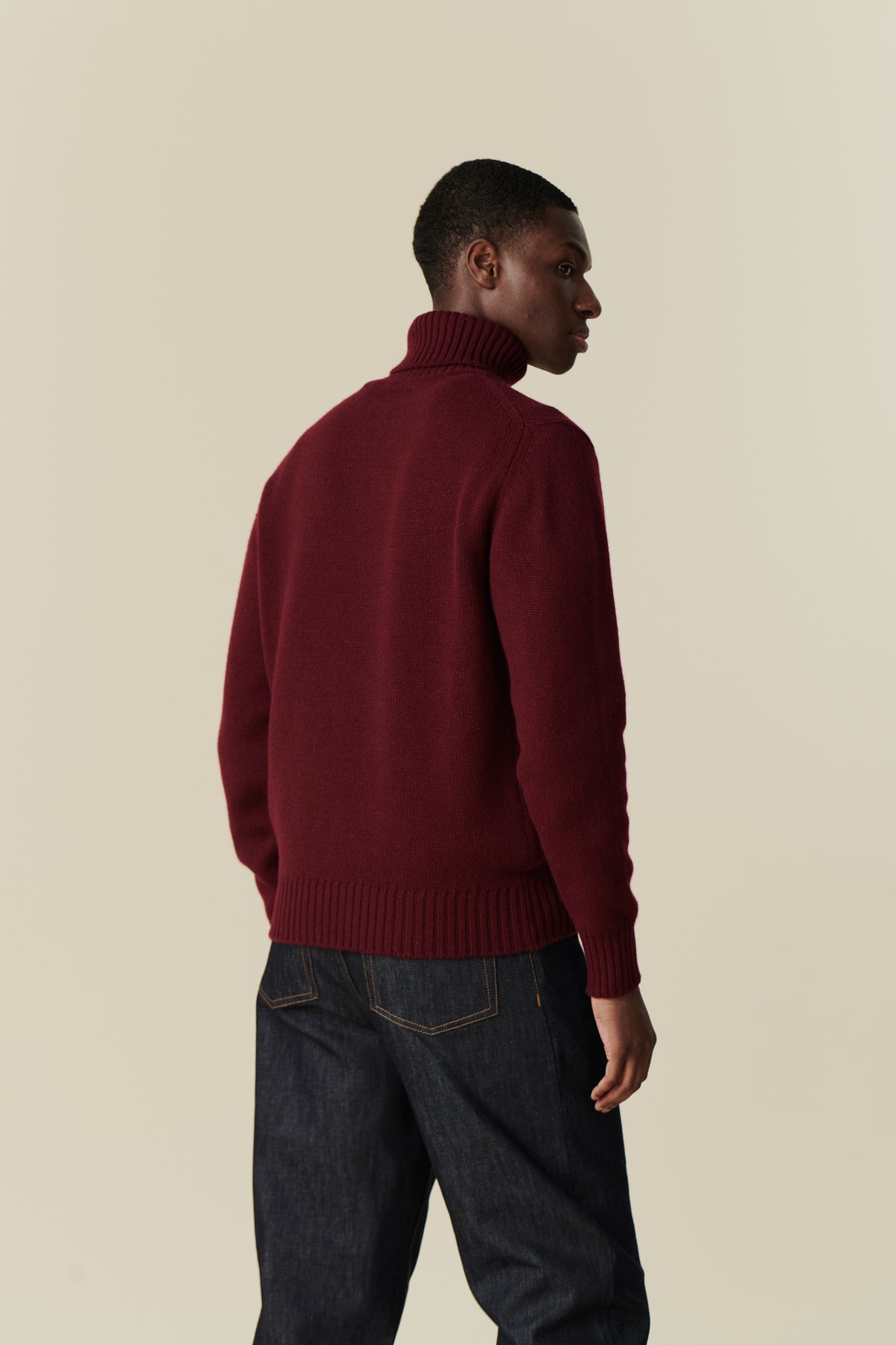 
            Back of male wearing lambswool roll neck in burgundy
