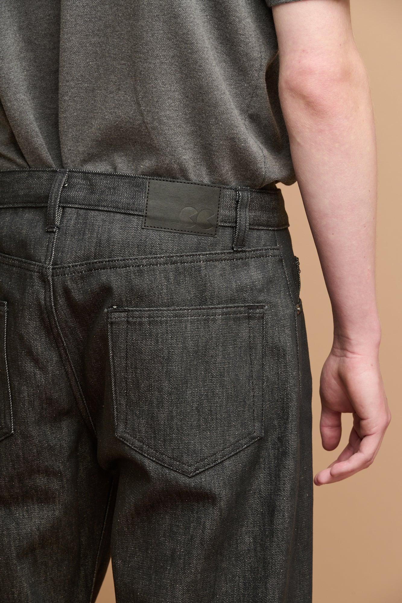 Close up of the back of button fly arran jean in black with black jeans patch on waistband