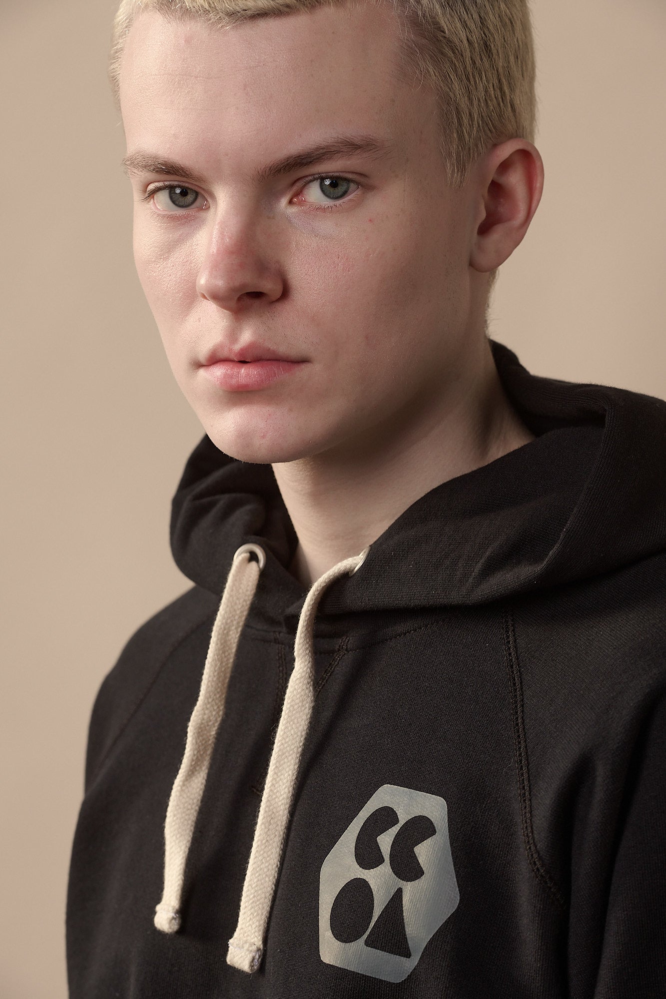 Portrait of male wearing men's raglan hooded sweatshirt in black with CCOA logo