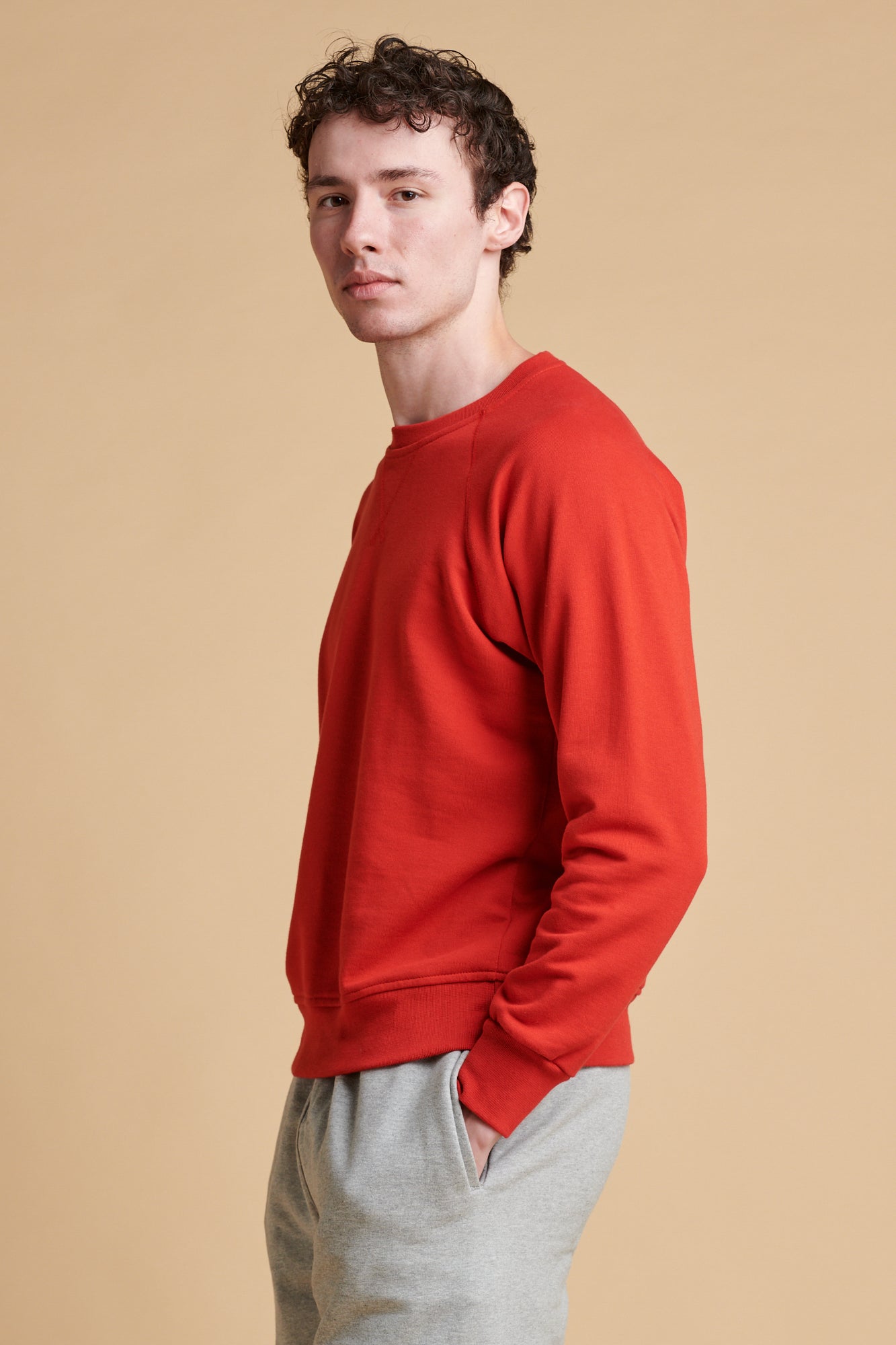 Thigh up of the side of male wearing raglan sweatshirt in crimson.