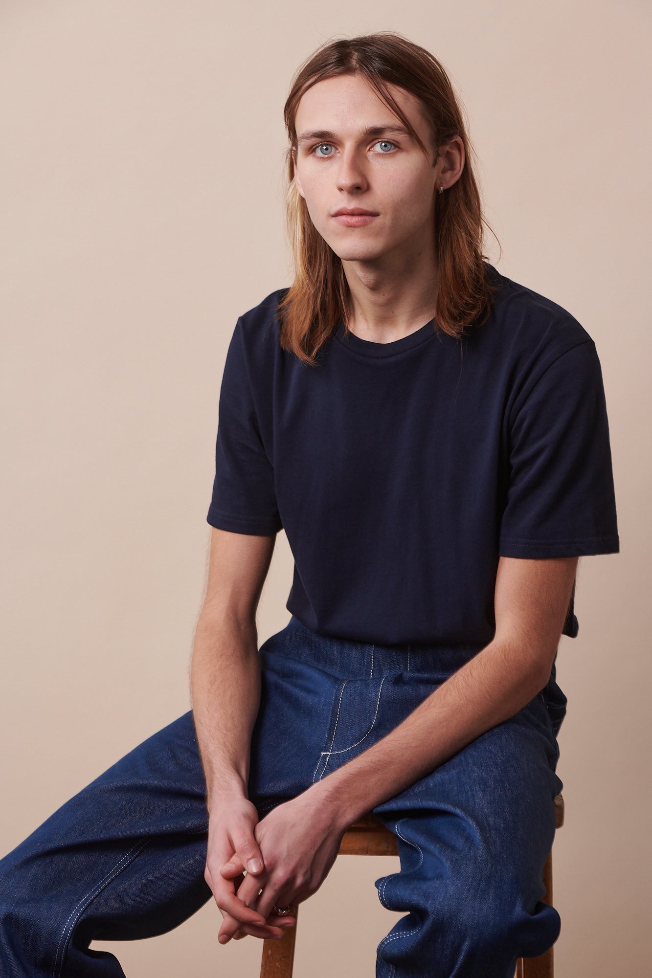 Male with shoulder length hair wearing short sleeve crew neck t shirt in navy
