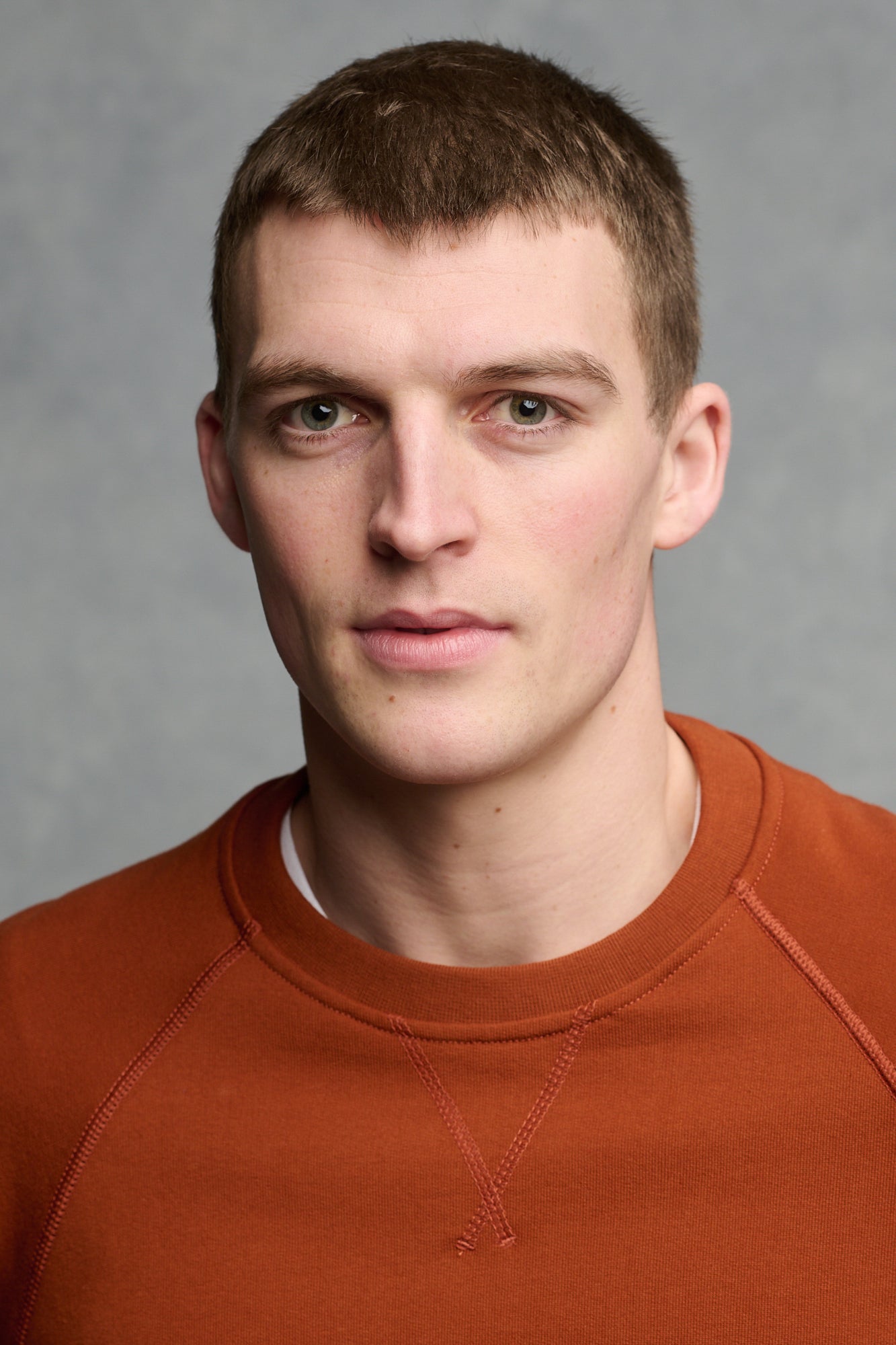 portrait of male wearing raglan sweatshirt in cinnamon worn over short sleeve crew neck t shirt in white