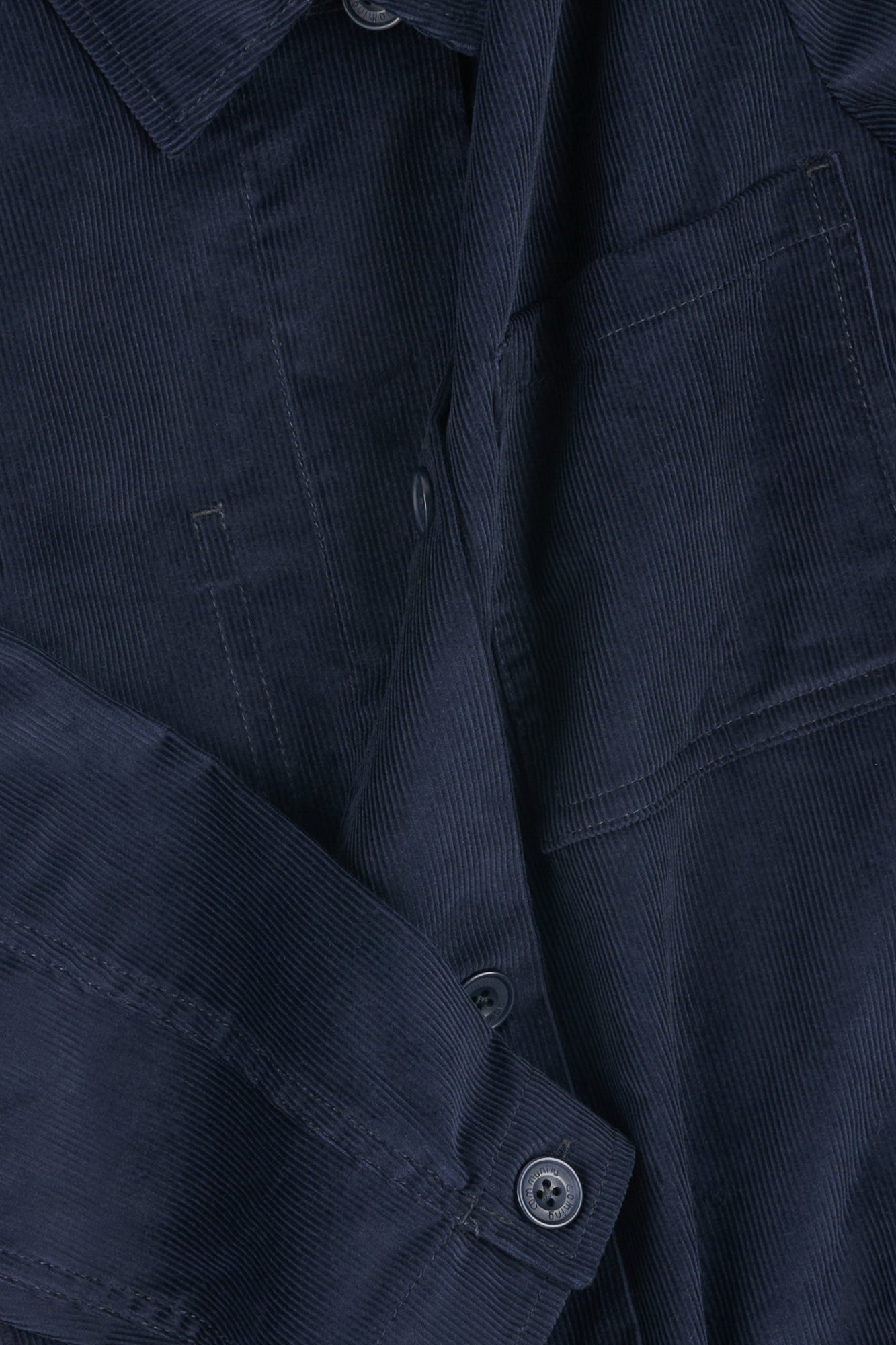 Close-up of a navy blue corduroy overshirt with buttons.