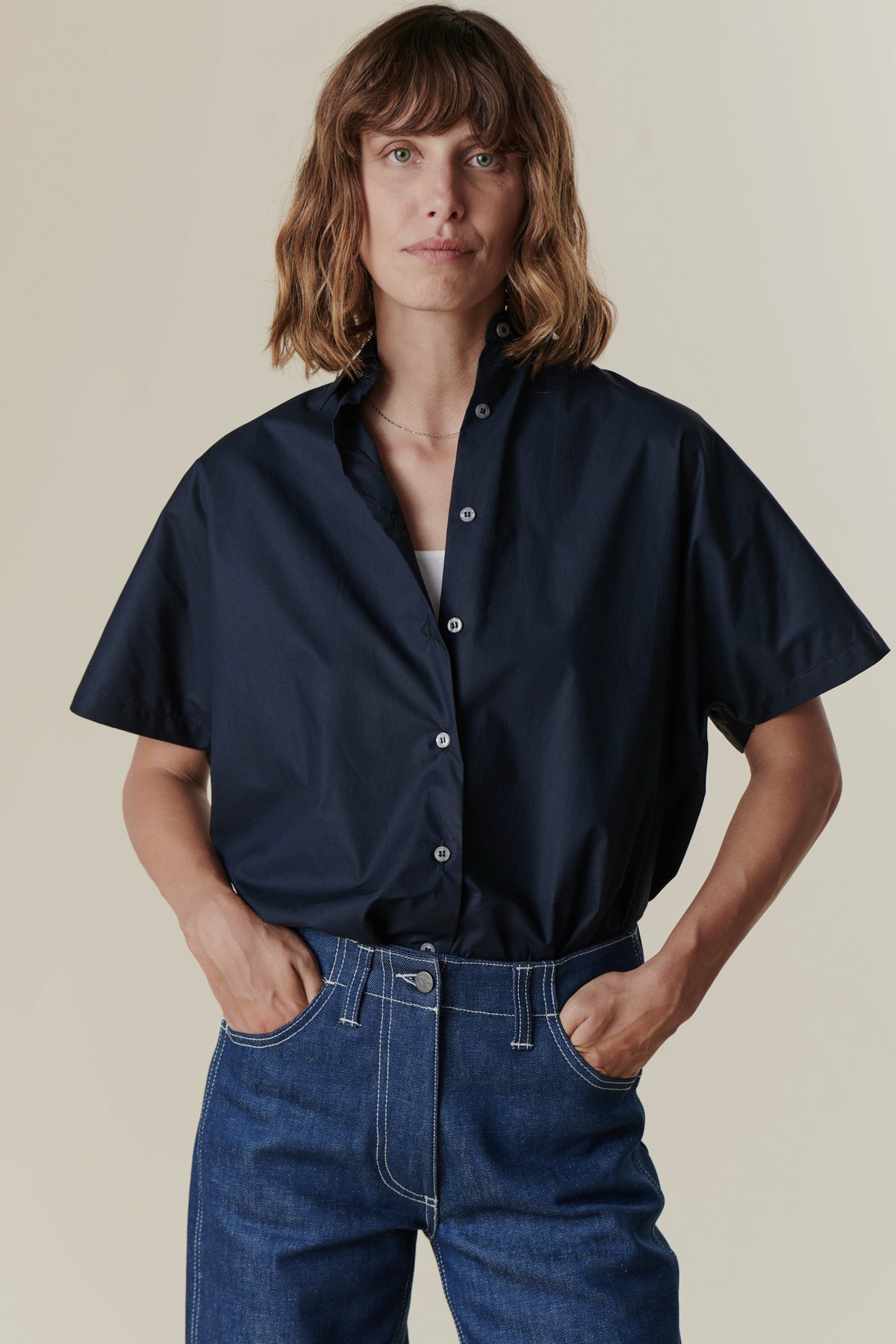 
            Woman with hands in jean pockets wearing the Ava short sleeve shirt in Navy