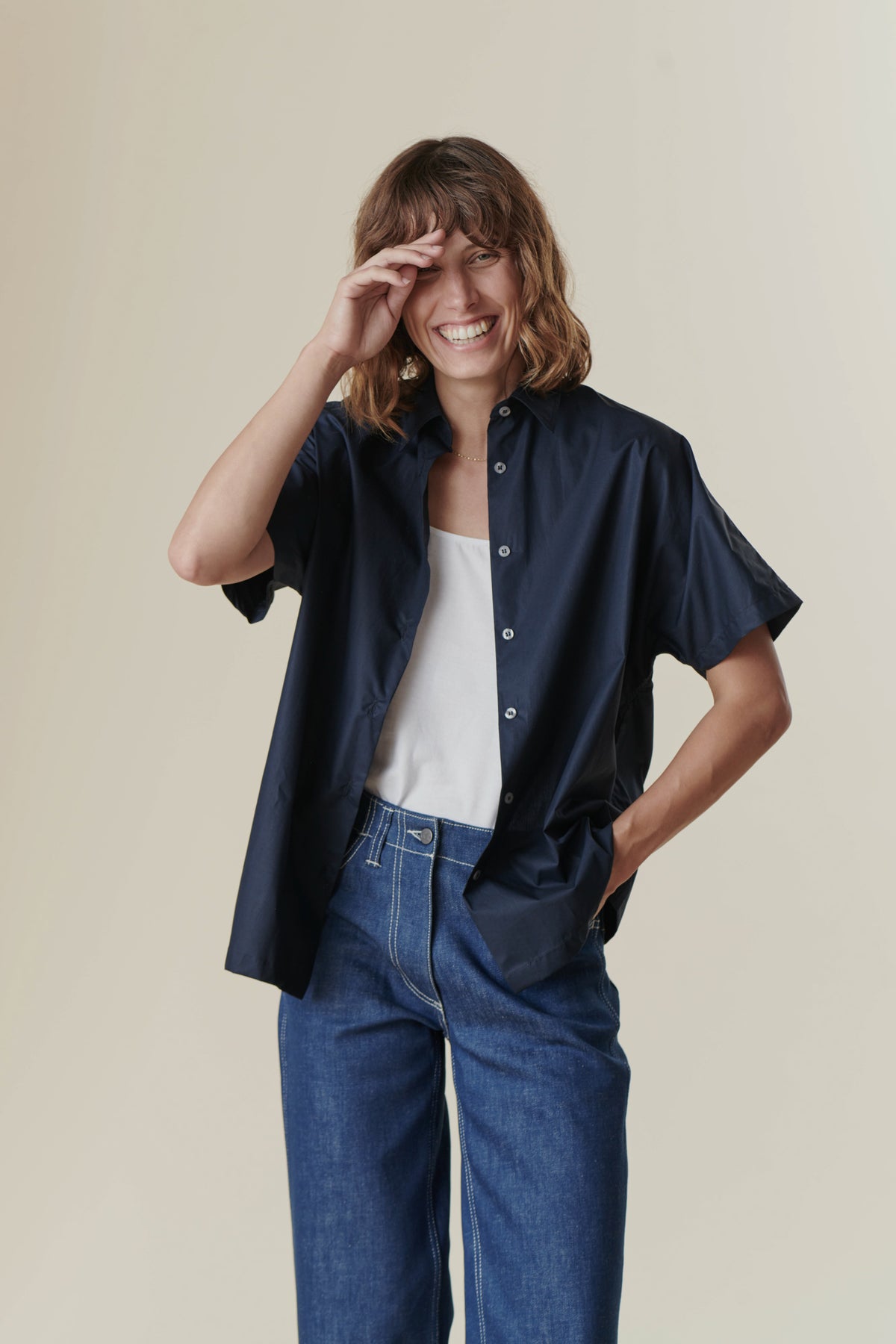 
            Smiling woman wearing Work Jeans and the short sleeve navy Ava shirt from Community Clothing.