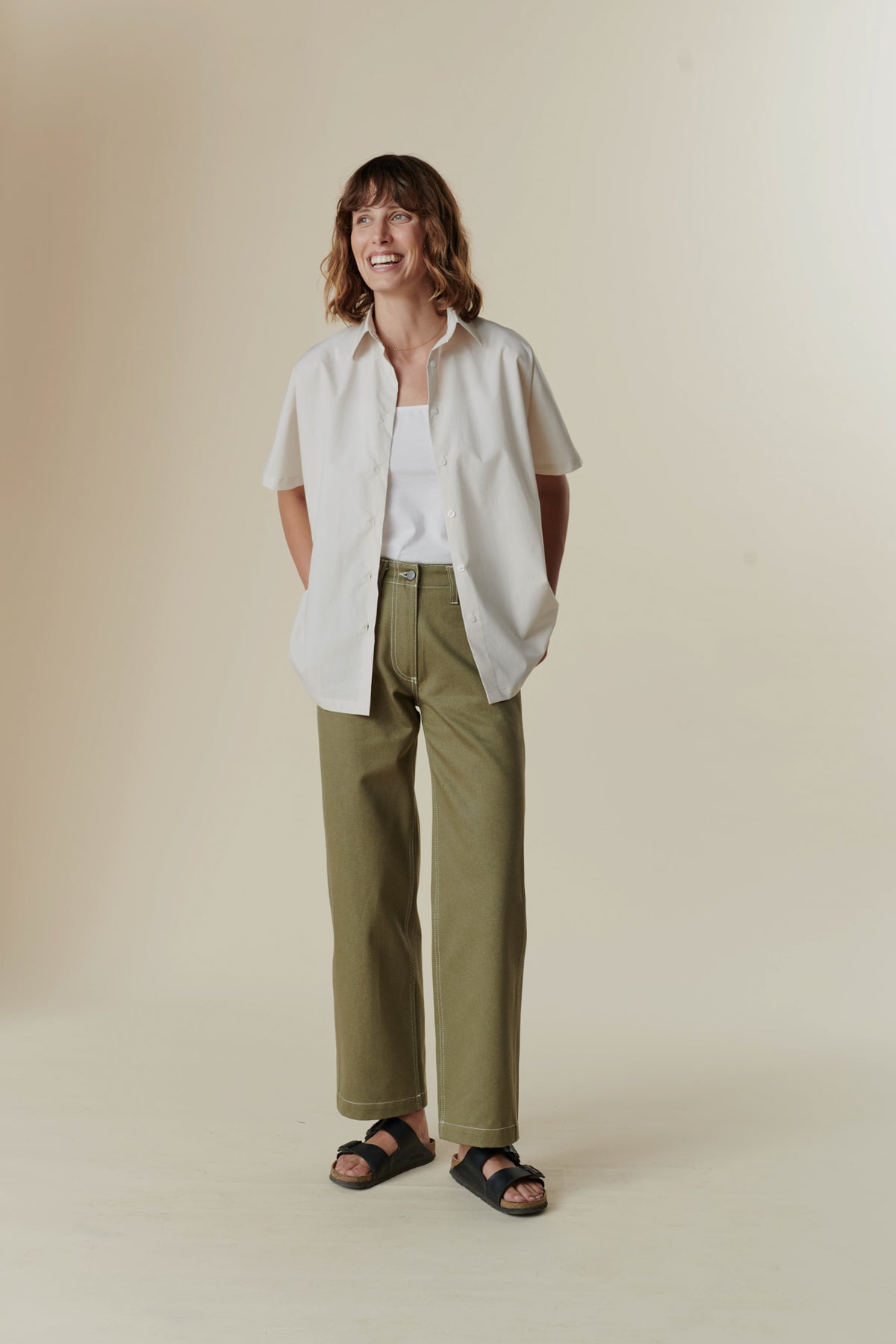 
            Woman smiling whilst wearing the Ava shirt and olive work jean