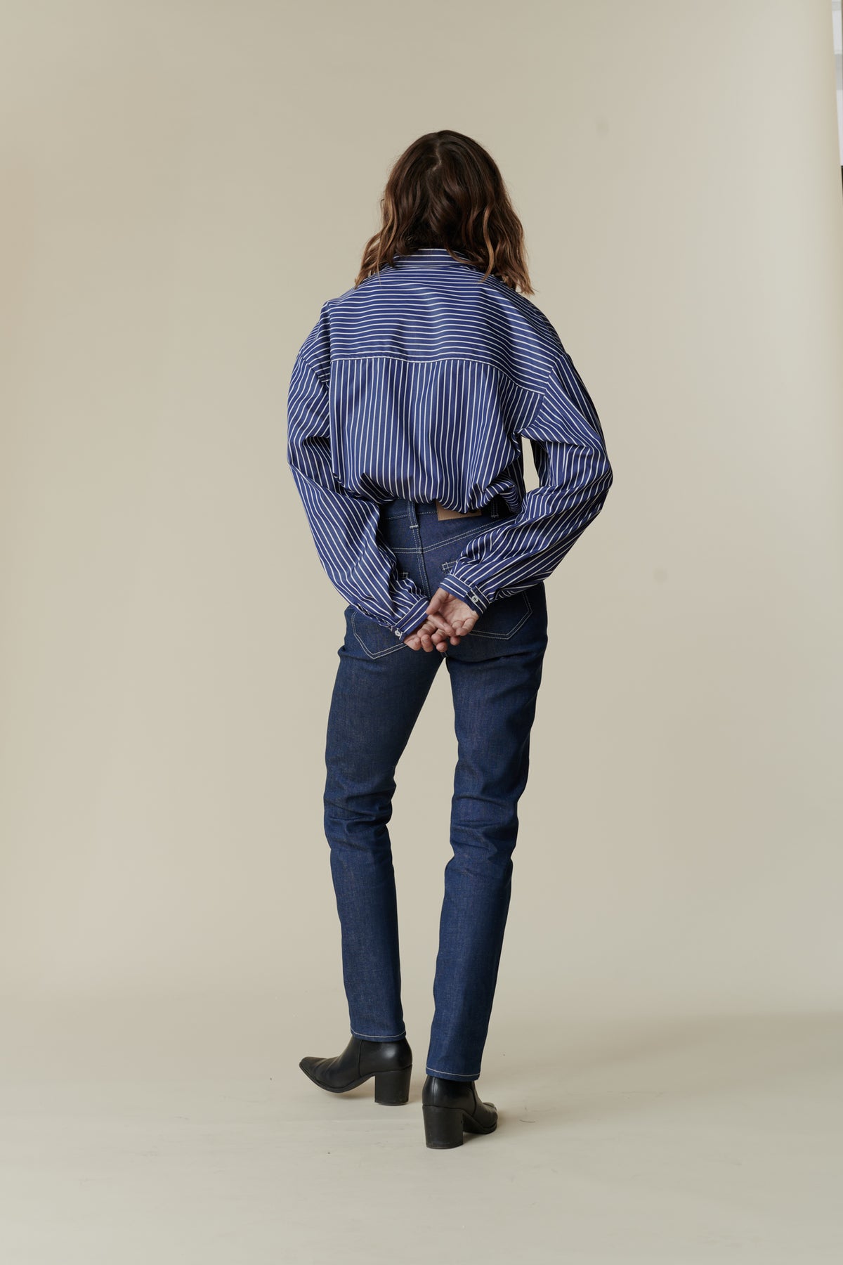 Full body back image of female wearing straight leg high rise jean blue