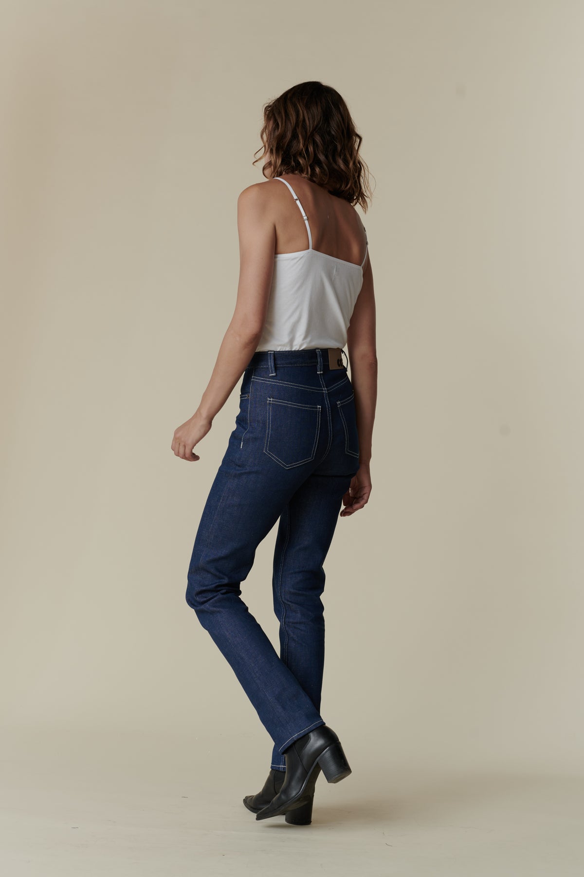 Full body back image of female wearing straight leg high rise jean in blue.