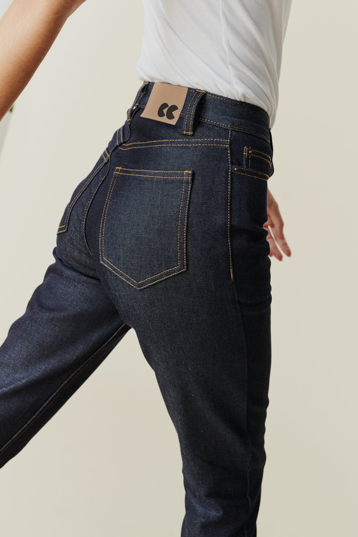 
            Back pocket and belt loop detail of female wearing straight leg high rise jeans in indigo