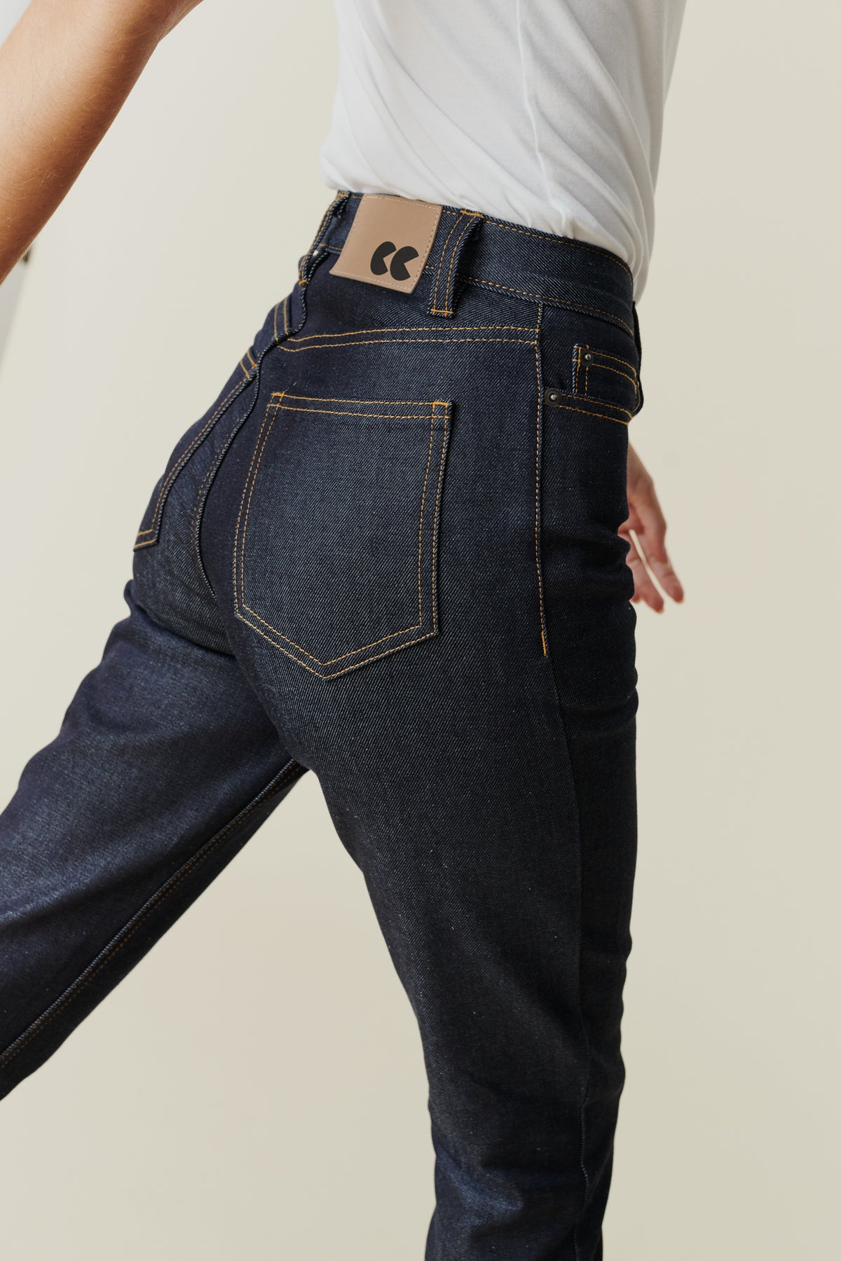 Back pocket and belt loop detail of female wearing straight leg high rise jeans in indigo