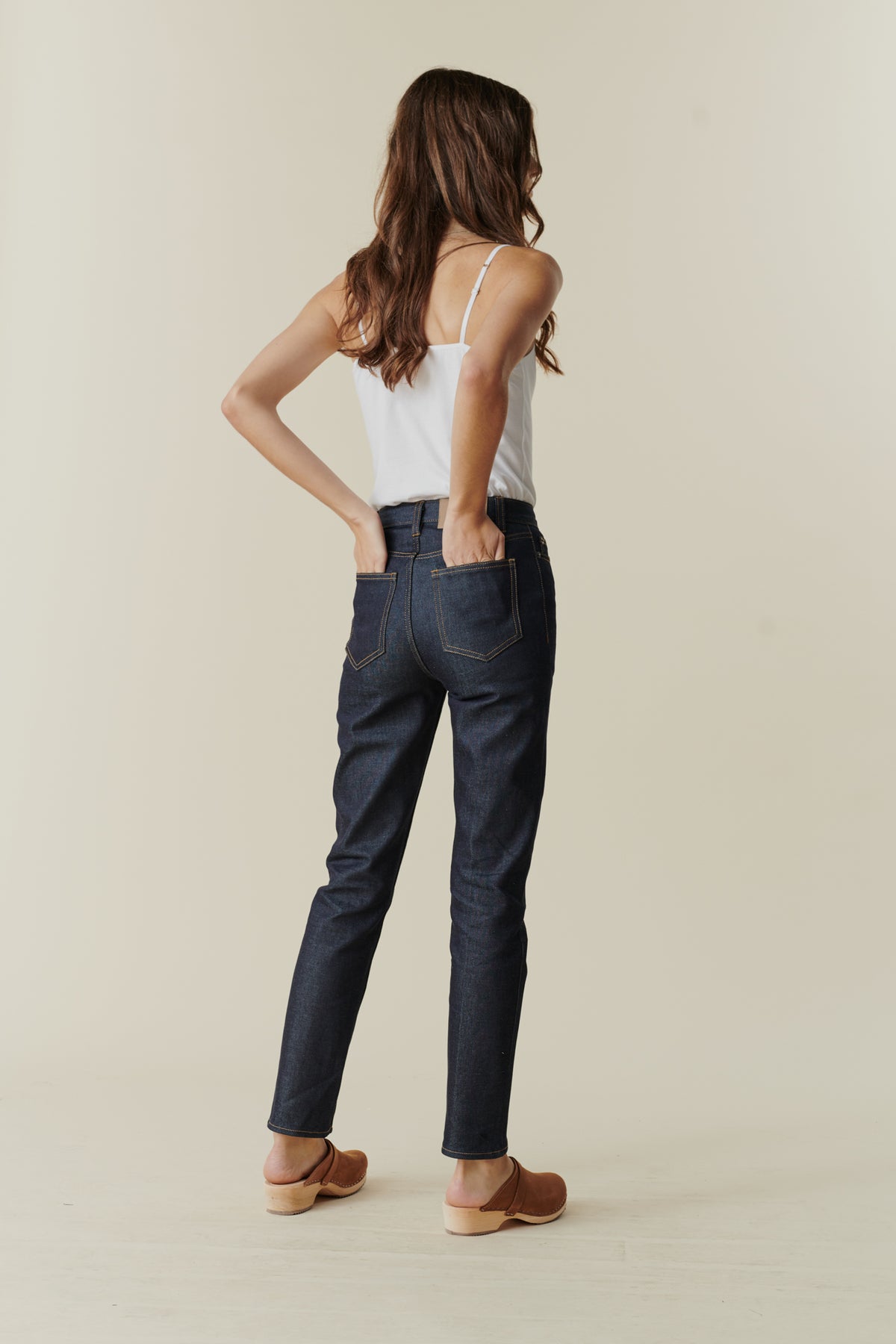 
            Full body image showing back of female wearing straight leg high rise jean in indigo with back pockets.
