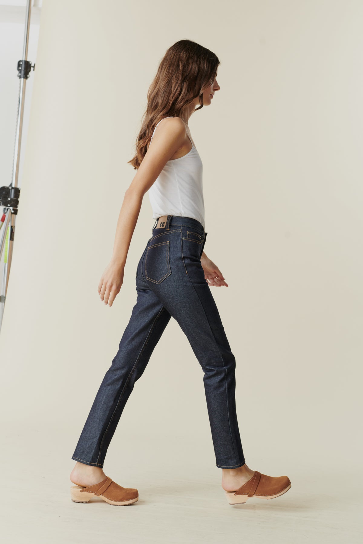 Full body side view of female wearing straight leg high rise jean in indigo.