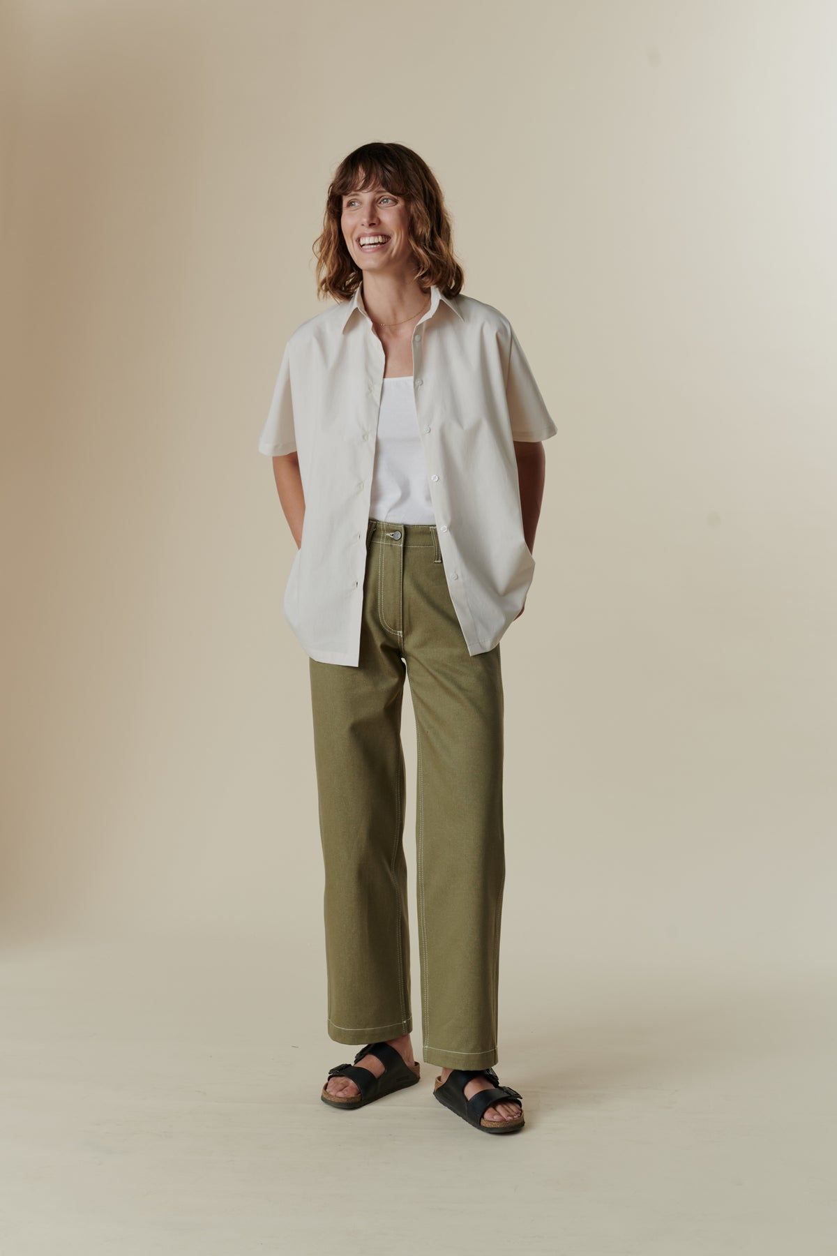 female wearing olive work jean with unbuttoned white ava shirt