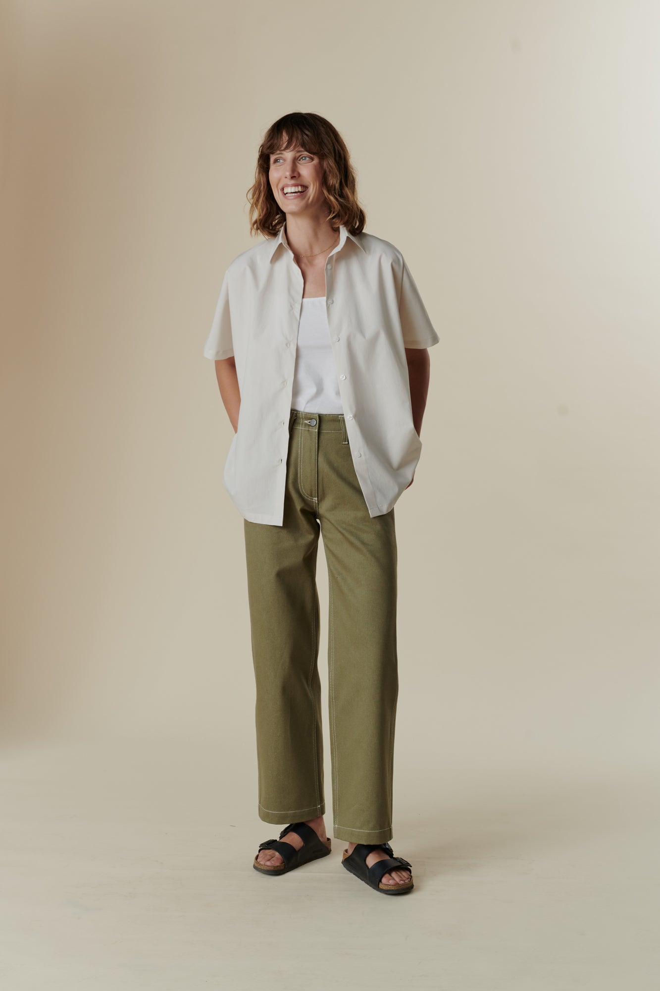 female wearing olive work jean with unbuttoned white ava shirt 