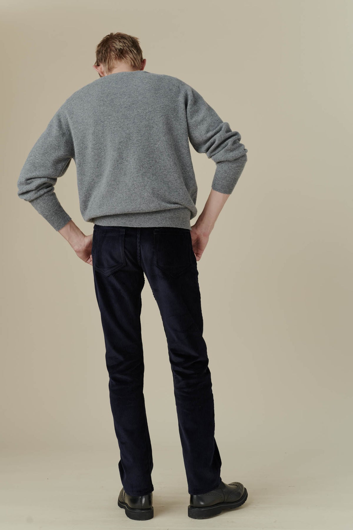 Back full body image of male wearing five pocket cord trousers in navy back