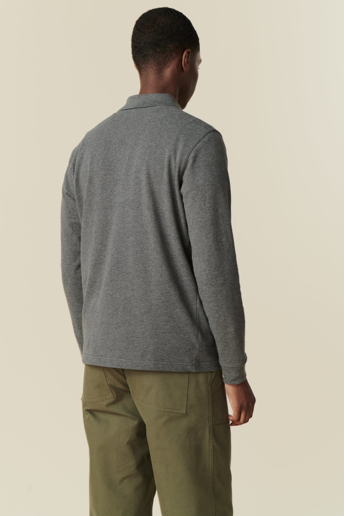 back shot of man wearing long sleeve grey marl polo with olive green combat pant