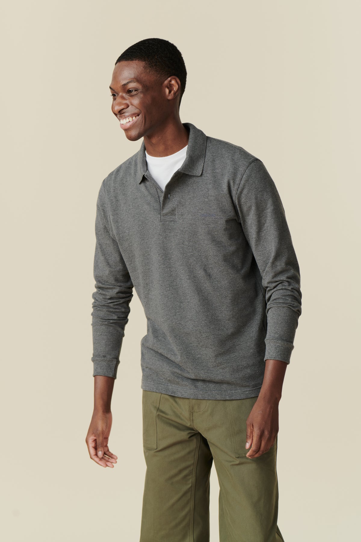 smiling male man wearing an unbuttoned grey marl polo shirt with arms down by his side