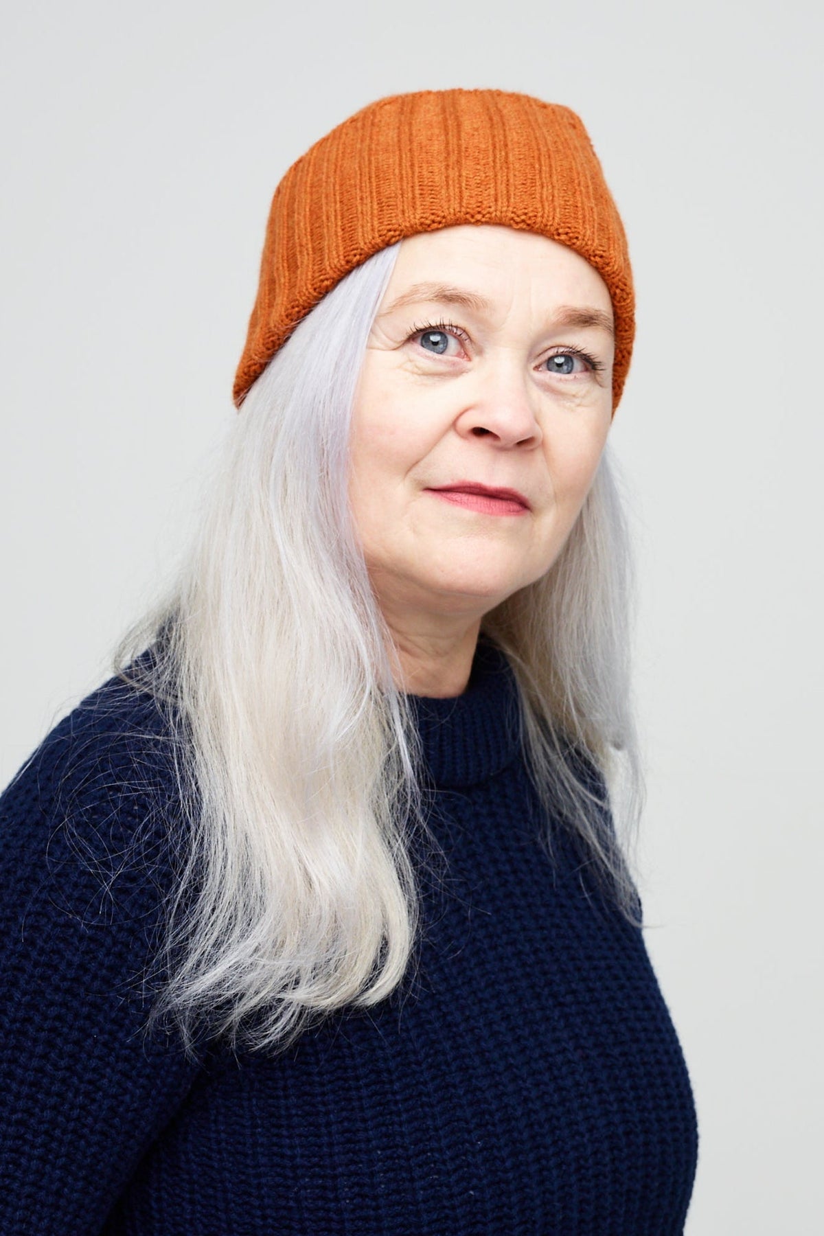 
            Female wearing unisex lambswool beanie hat in rust