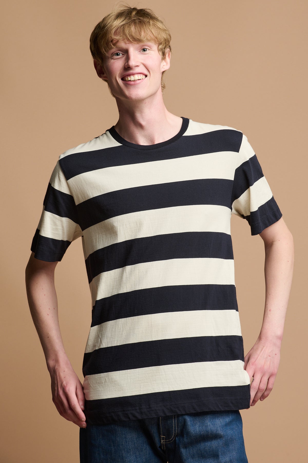 
            Smiley male wearing wide stripe t shirt in ecru navy paired with blue jeans