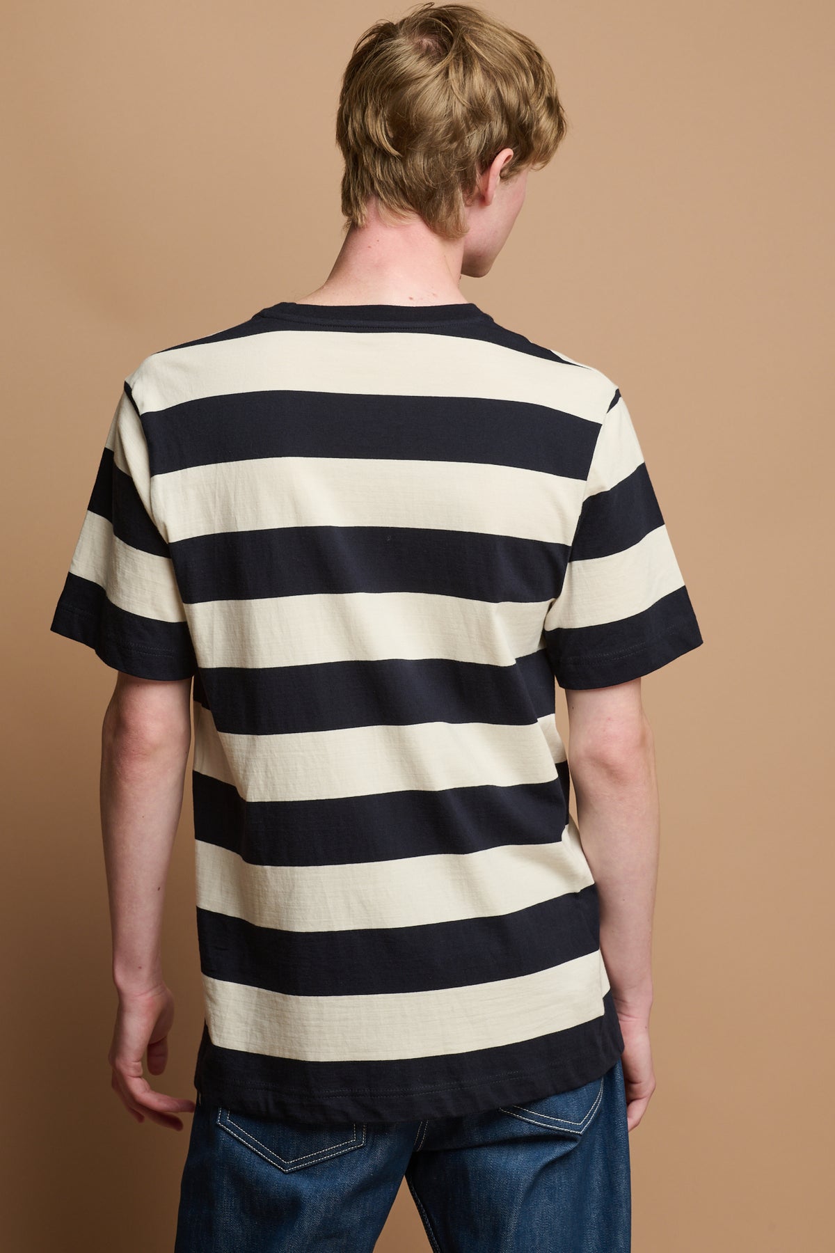 
            the back of male wearing ecru and navy stripe short sleeved t shirt